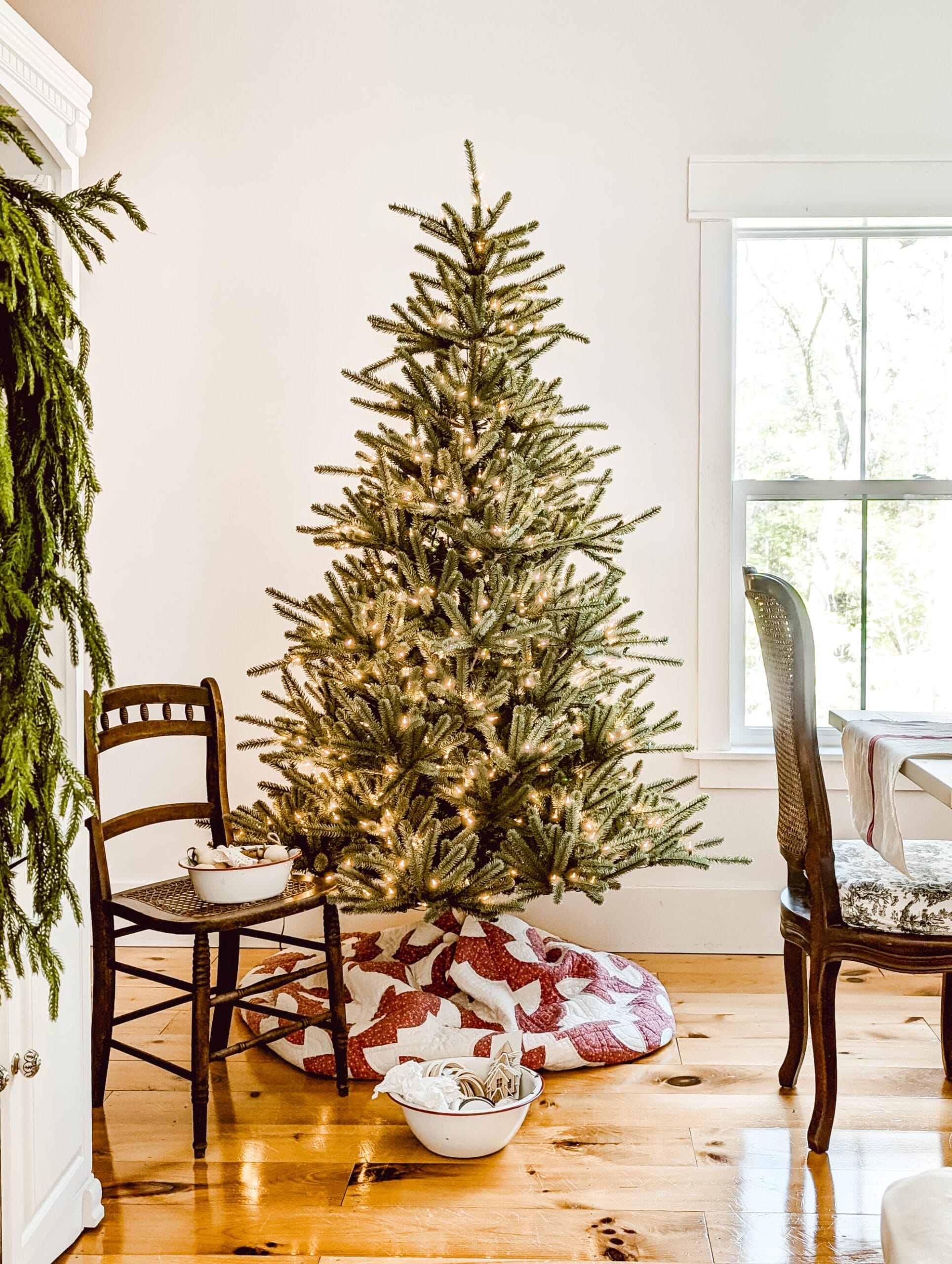 Balsam Hill's Sanibel Spruce Christmas tree fluffed but with no ornaments, and with a vintage quilt as a tree skirt