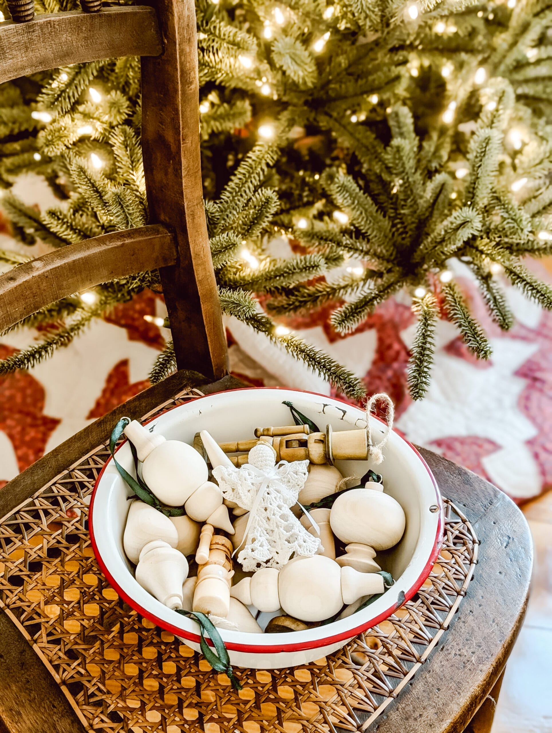 antique white and red enamel bowl full of wooden finial Christmas ornaments on an antique caned wood chair