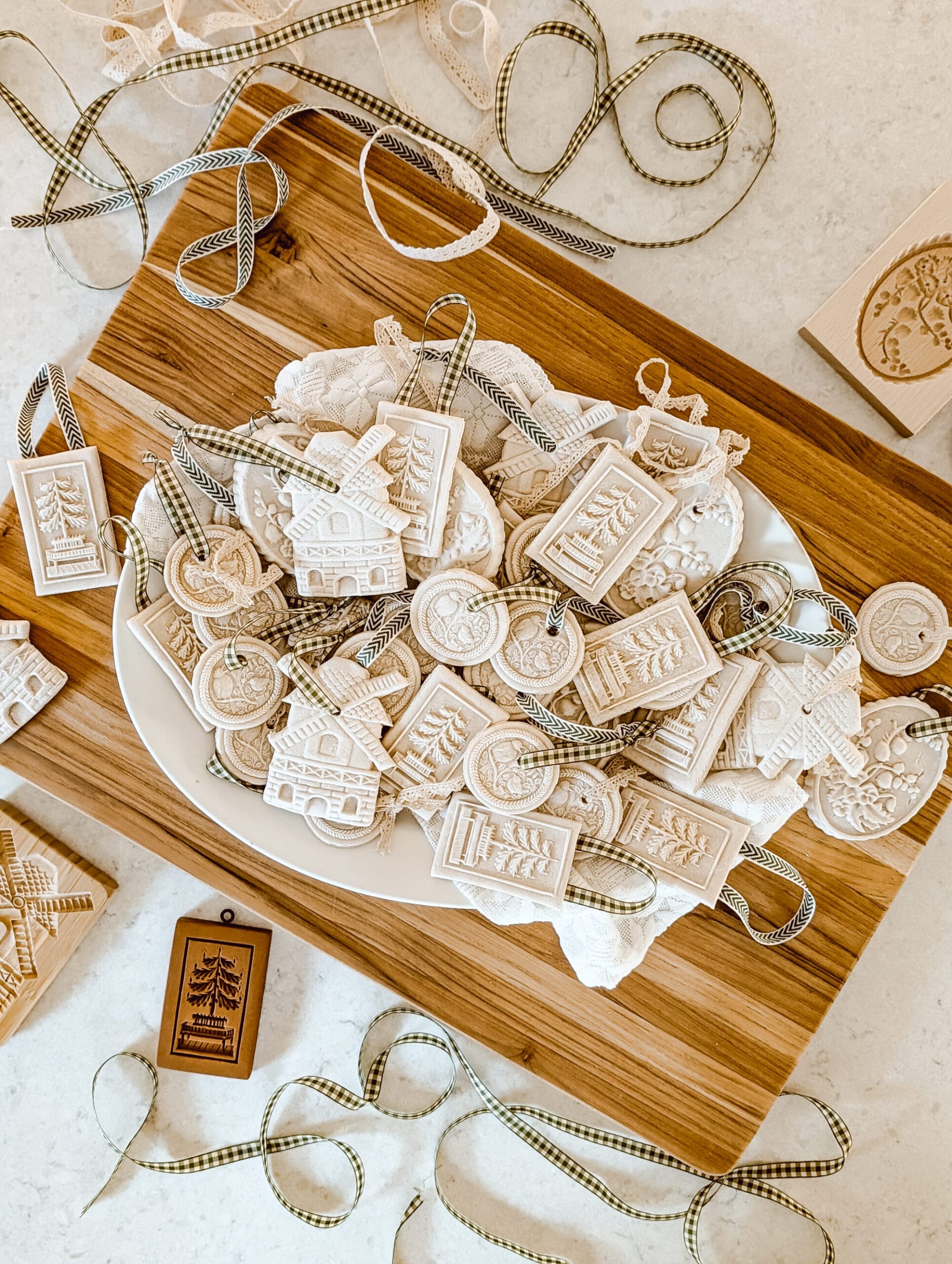 fancy salt dough Christmas ornaments on a white platter stacked on a wood cutting board