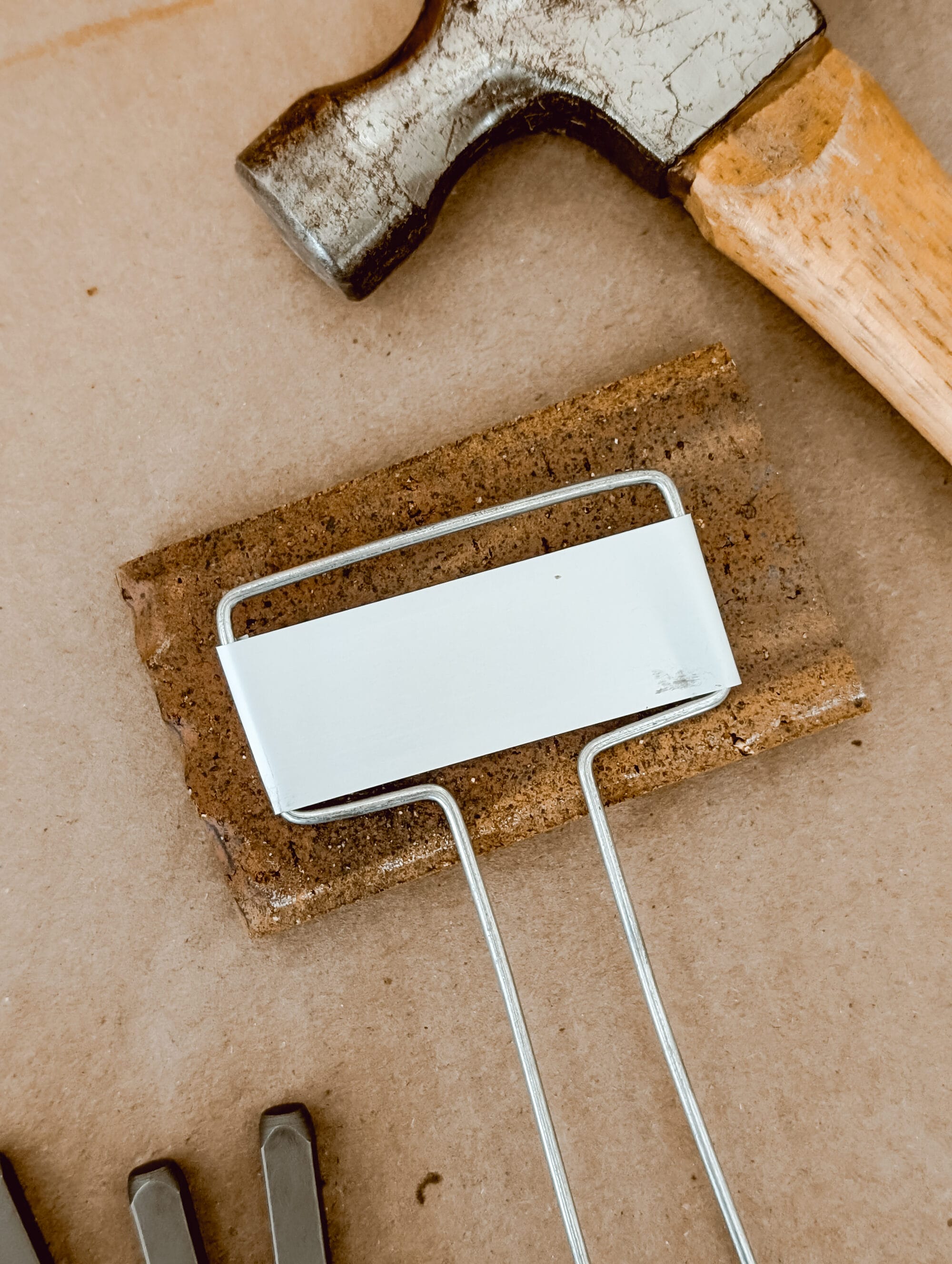 a metal plant marker laying on top of a brick on top of a piece of cardboard