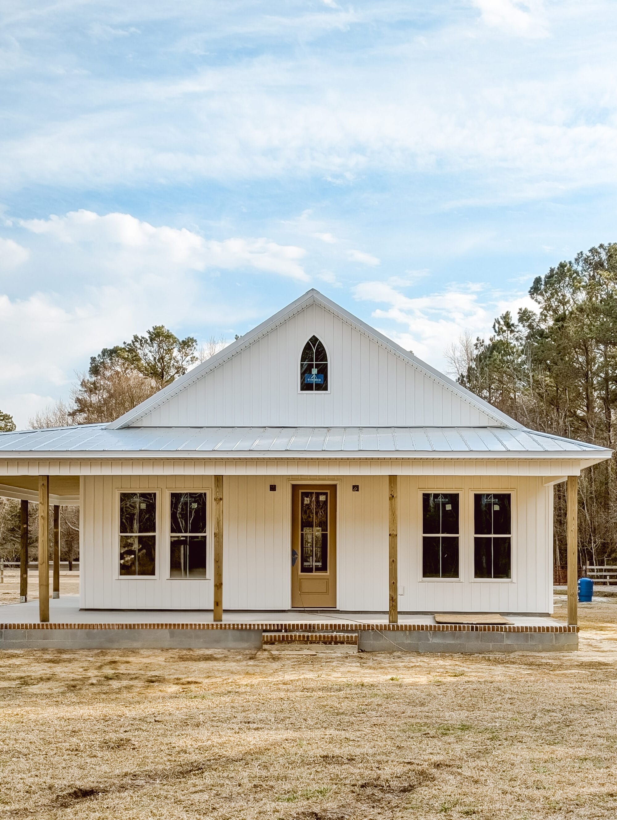 building a new cottage to look like an old Carpenter Gothic style home with white board and batten siding and a pointed arch window