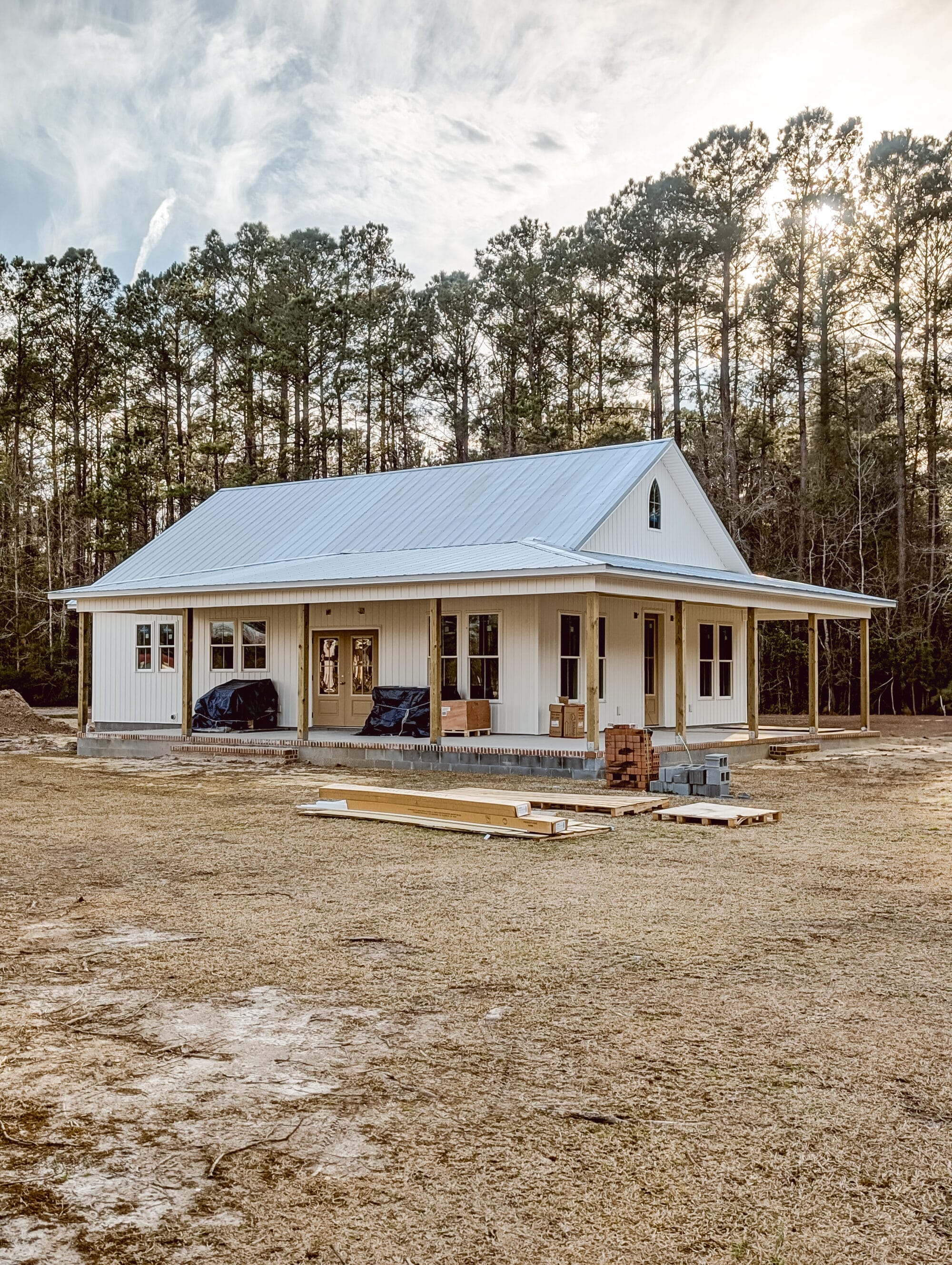 new old cottage still under construction with white board and batten siding and a galvanized metal roof