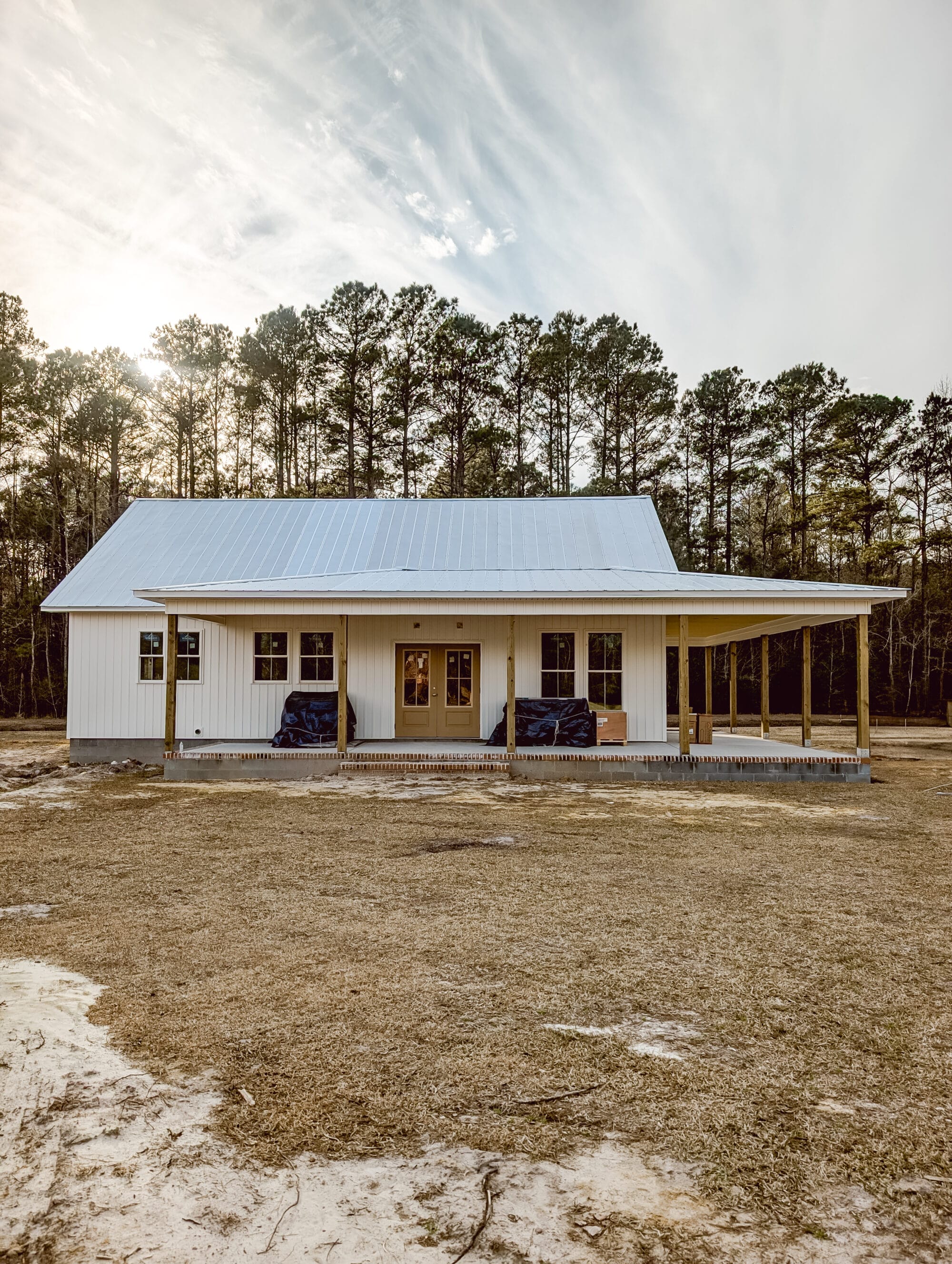 side porch on a small 2 bedroom cottage with white board and batten siding and a galvanized metal roof