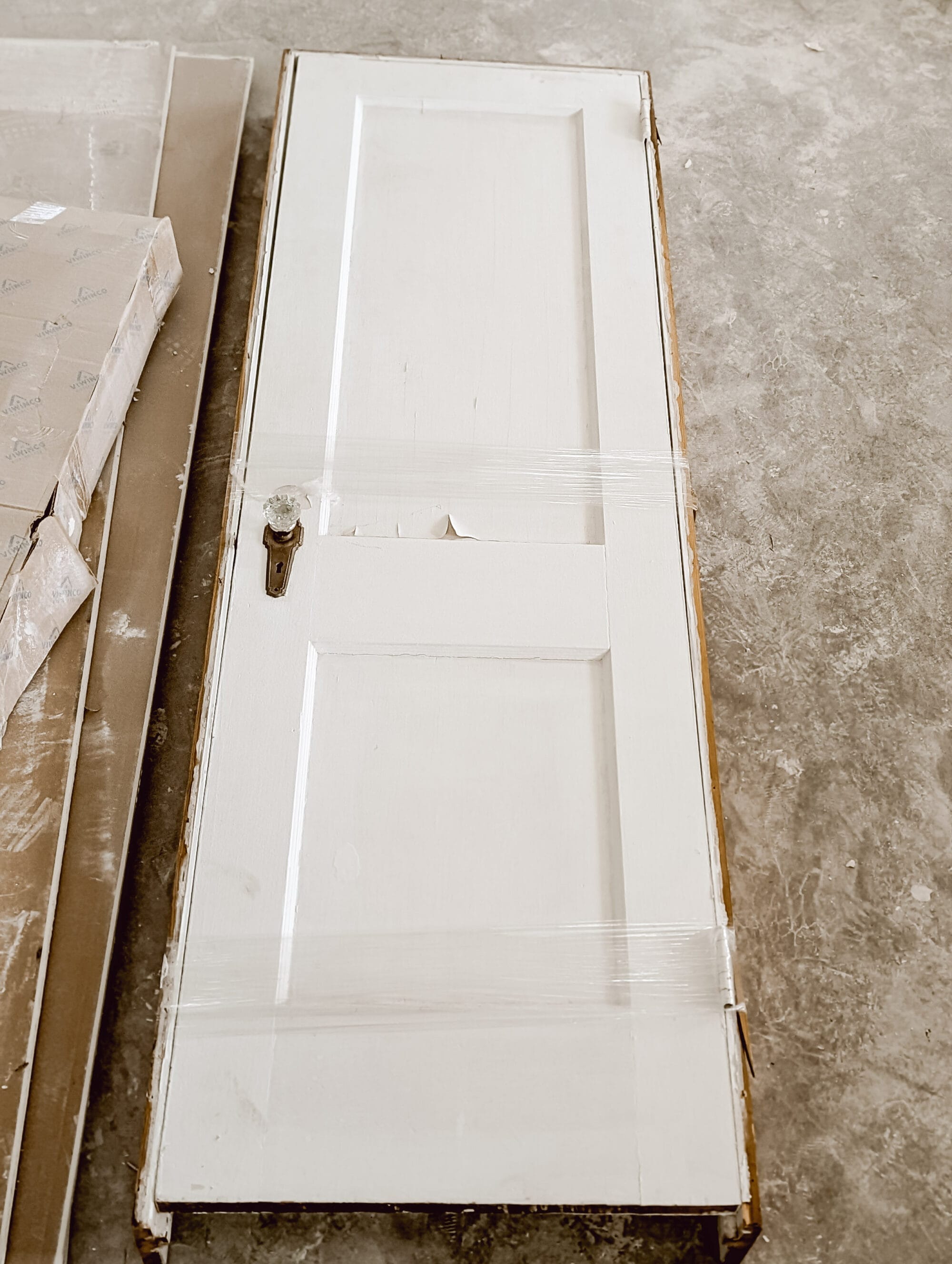 salvaged antique door with white chippy paint and the original brass and crystal door knobs