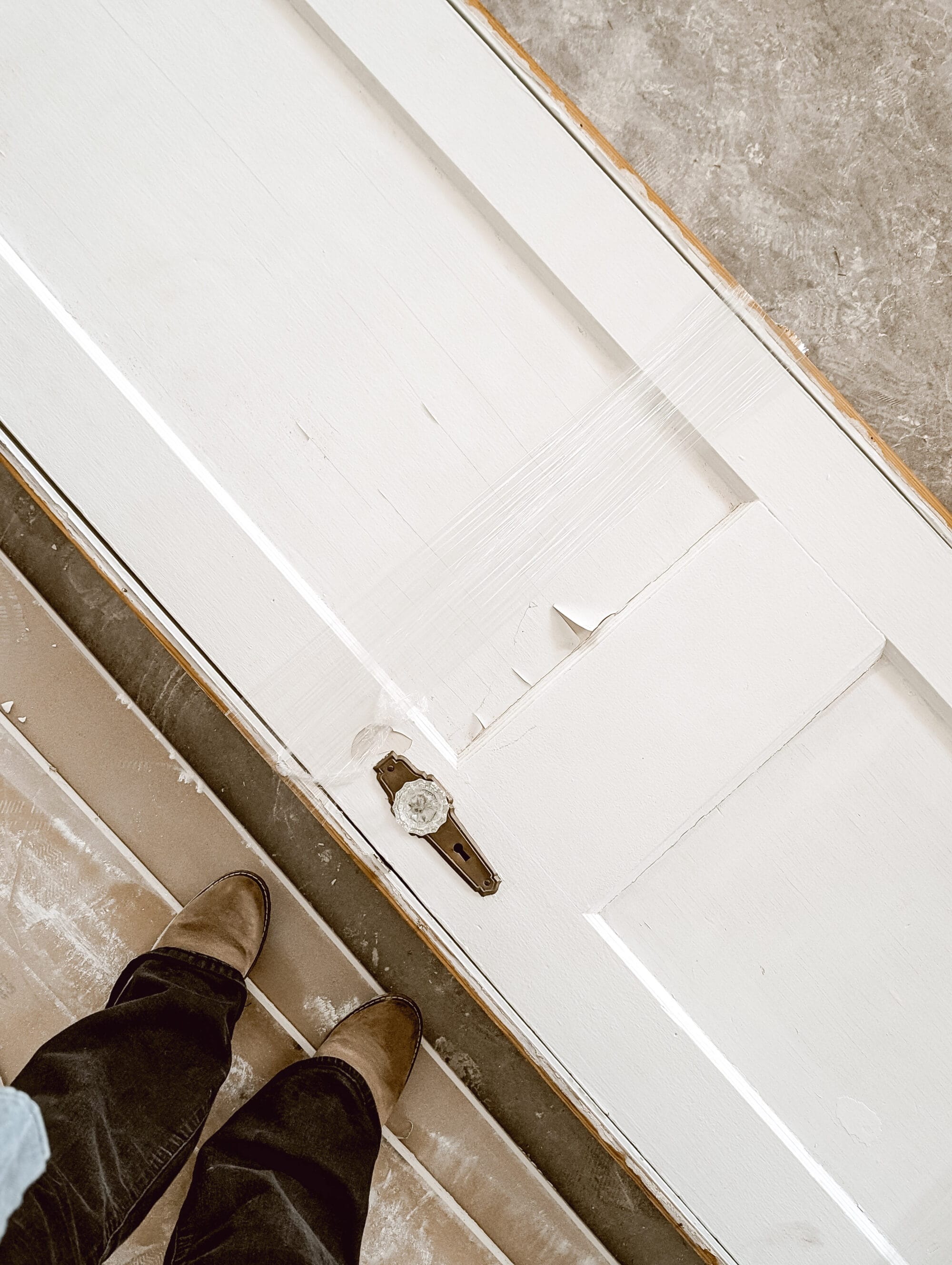 salvaged antique door with white chippy paint and the original brass and crystal door knobs