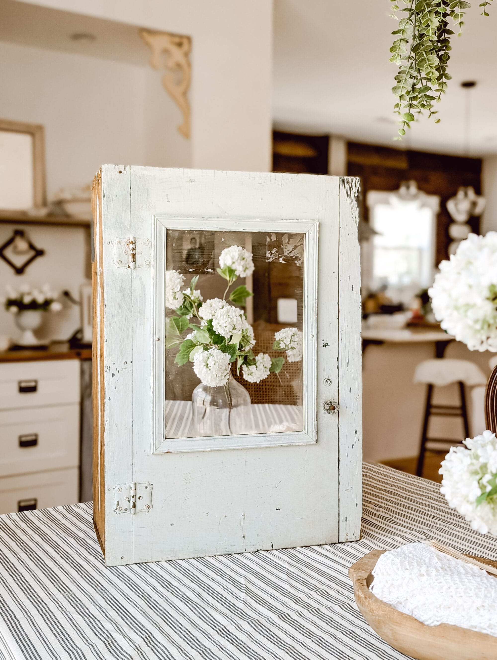 chippy painted vintage wood medicine cabinet with a mirror on the door and a glass knob