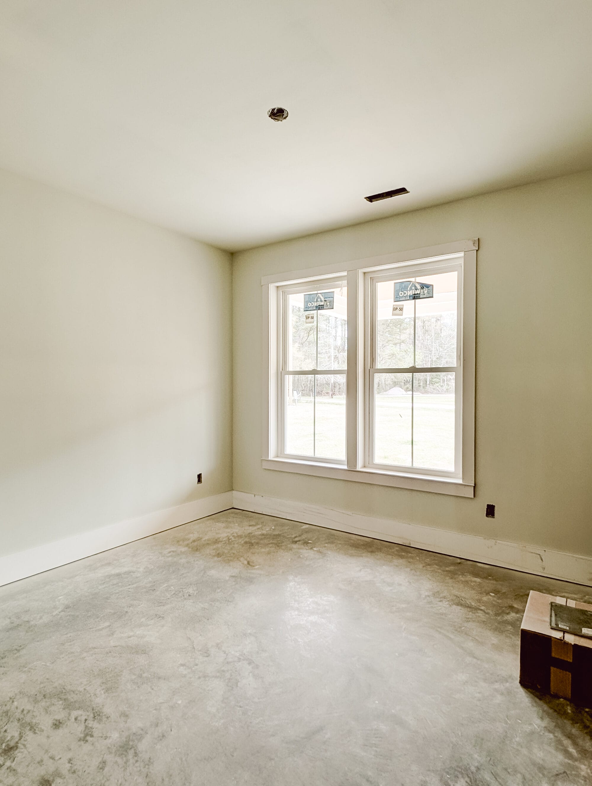 framed double windows with primed walls and concrete floors in our unfinished guest bedroom