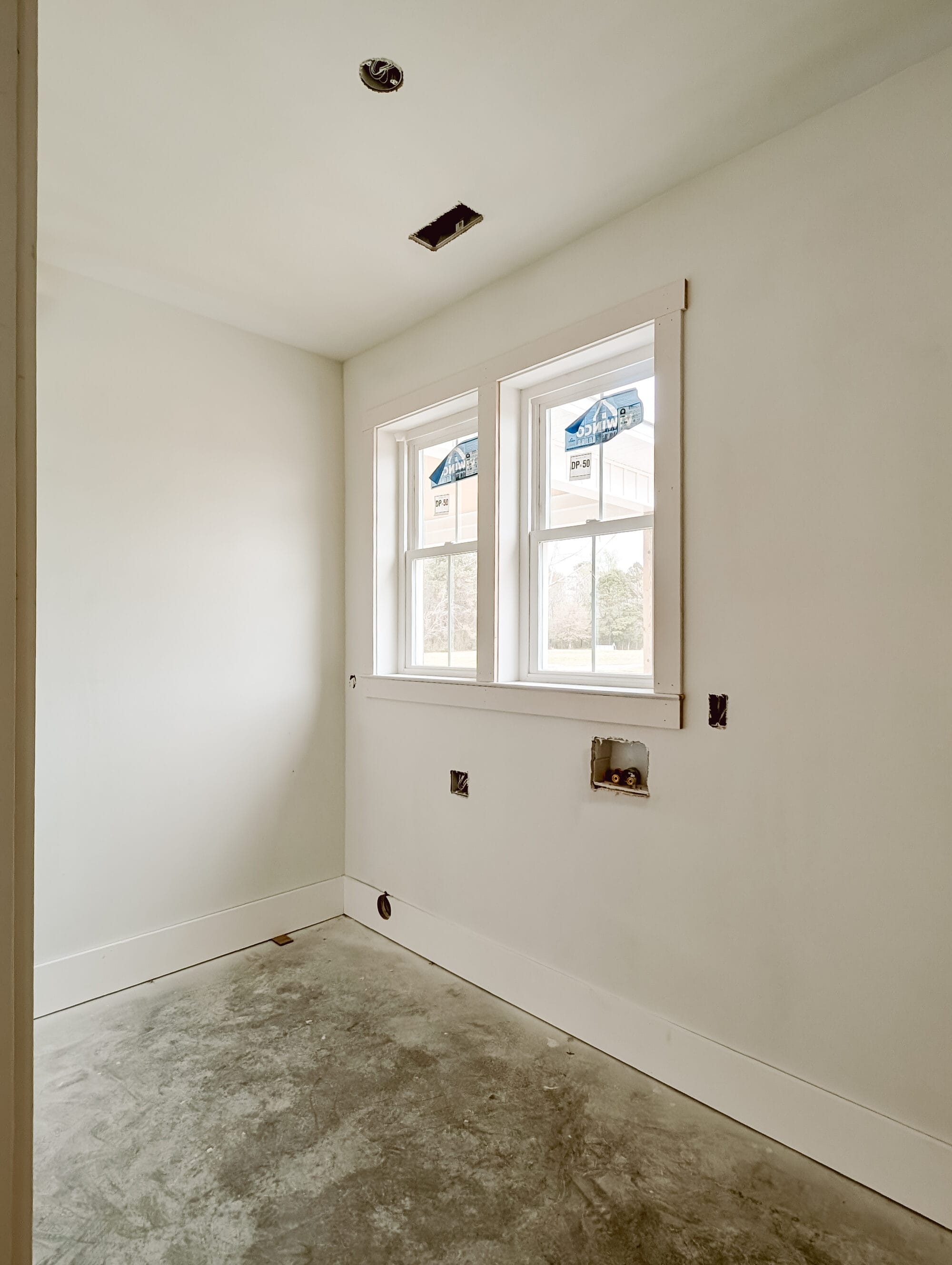 unfinished laundry room with windows over the space for the washer and dryer