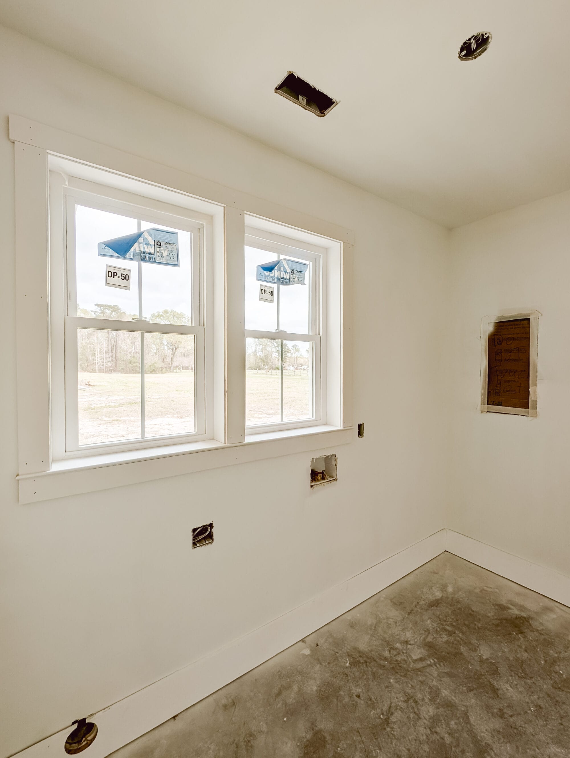 unfinished laundry room with windows over the space for the washer and dryer