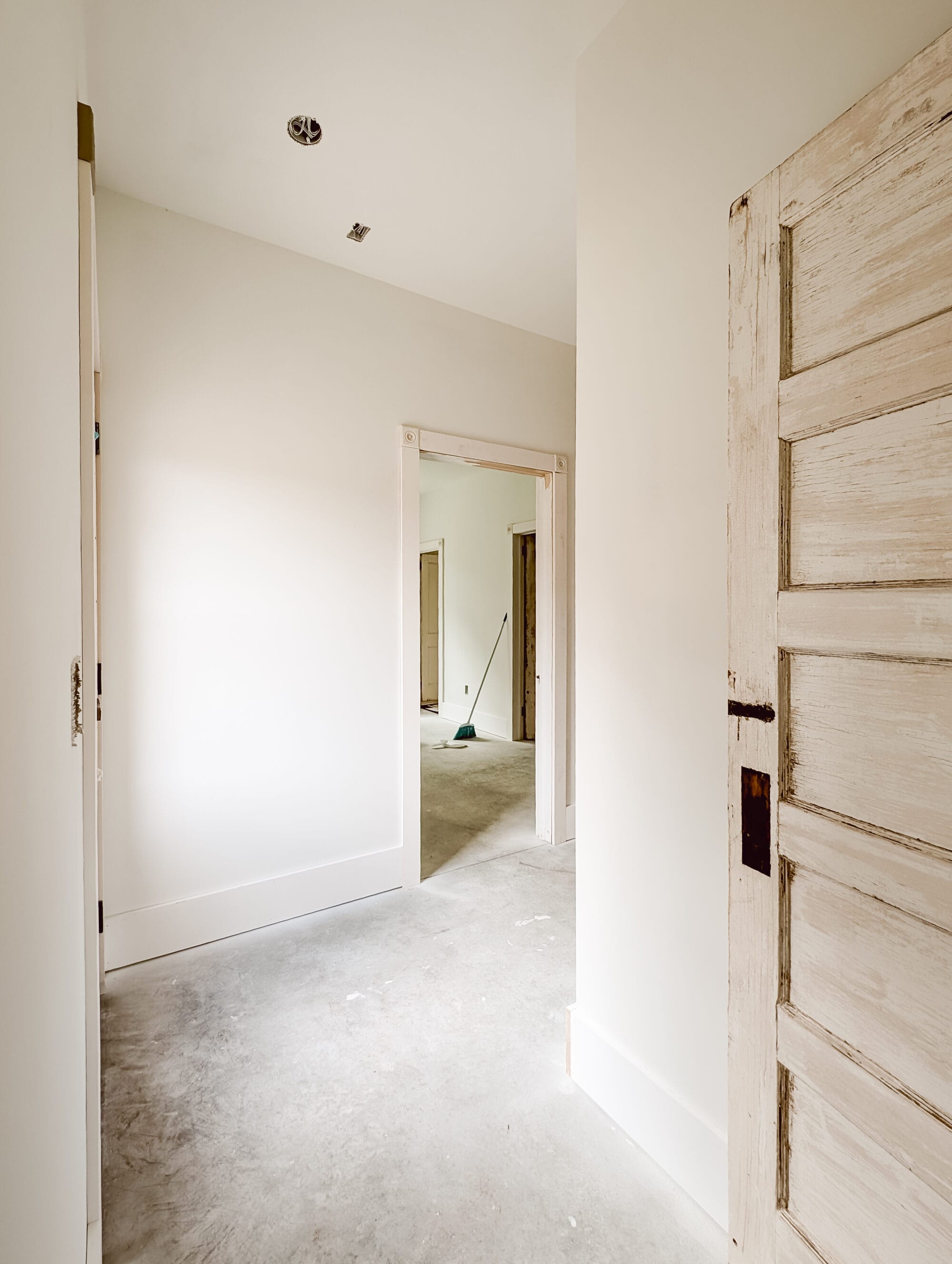 "L" shaped hallway with antique doors into the laundry room and into the primary suite