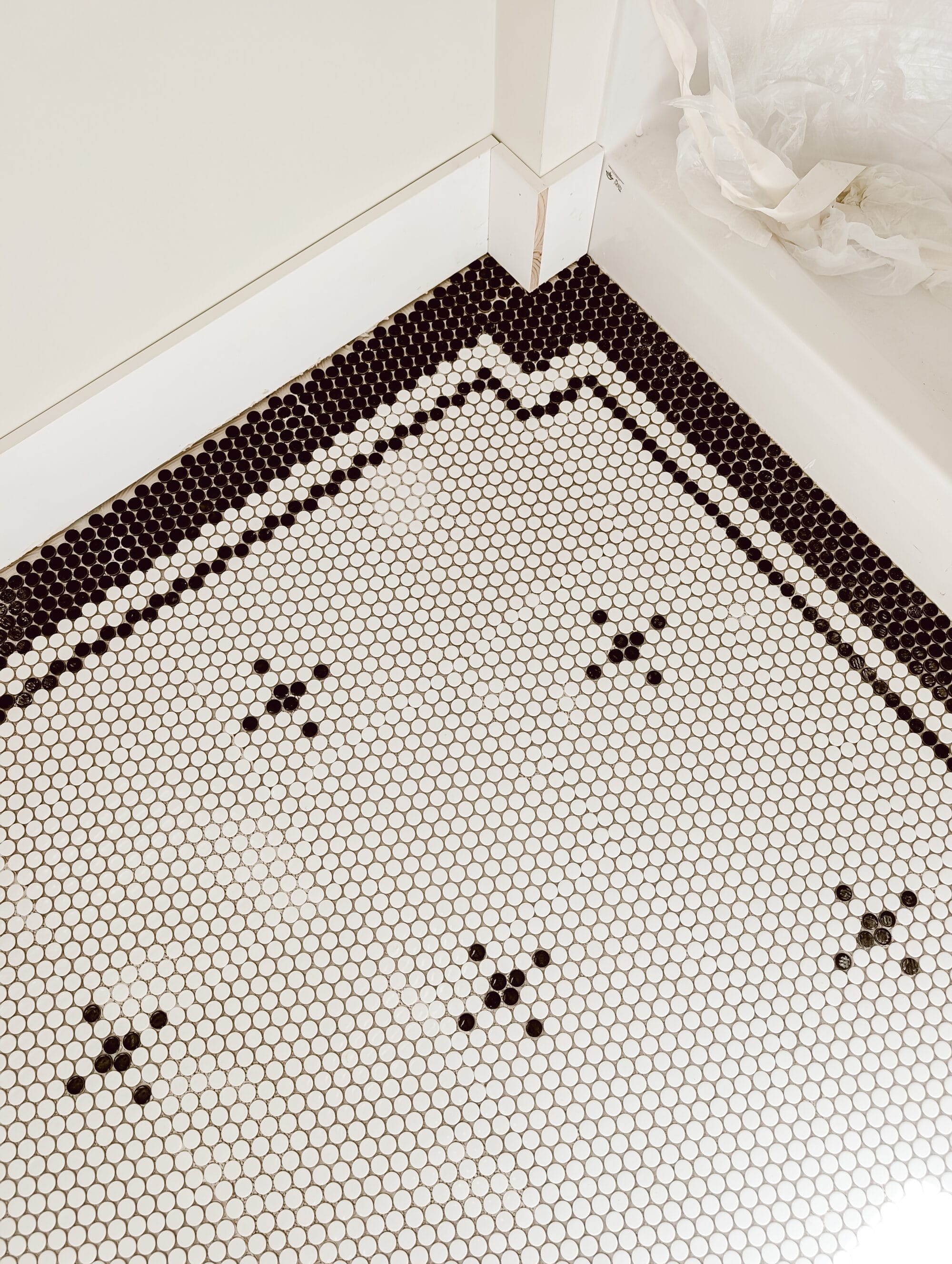 classic black and white penny tile floor pattern with a double border that juts out around the shower wall