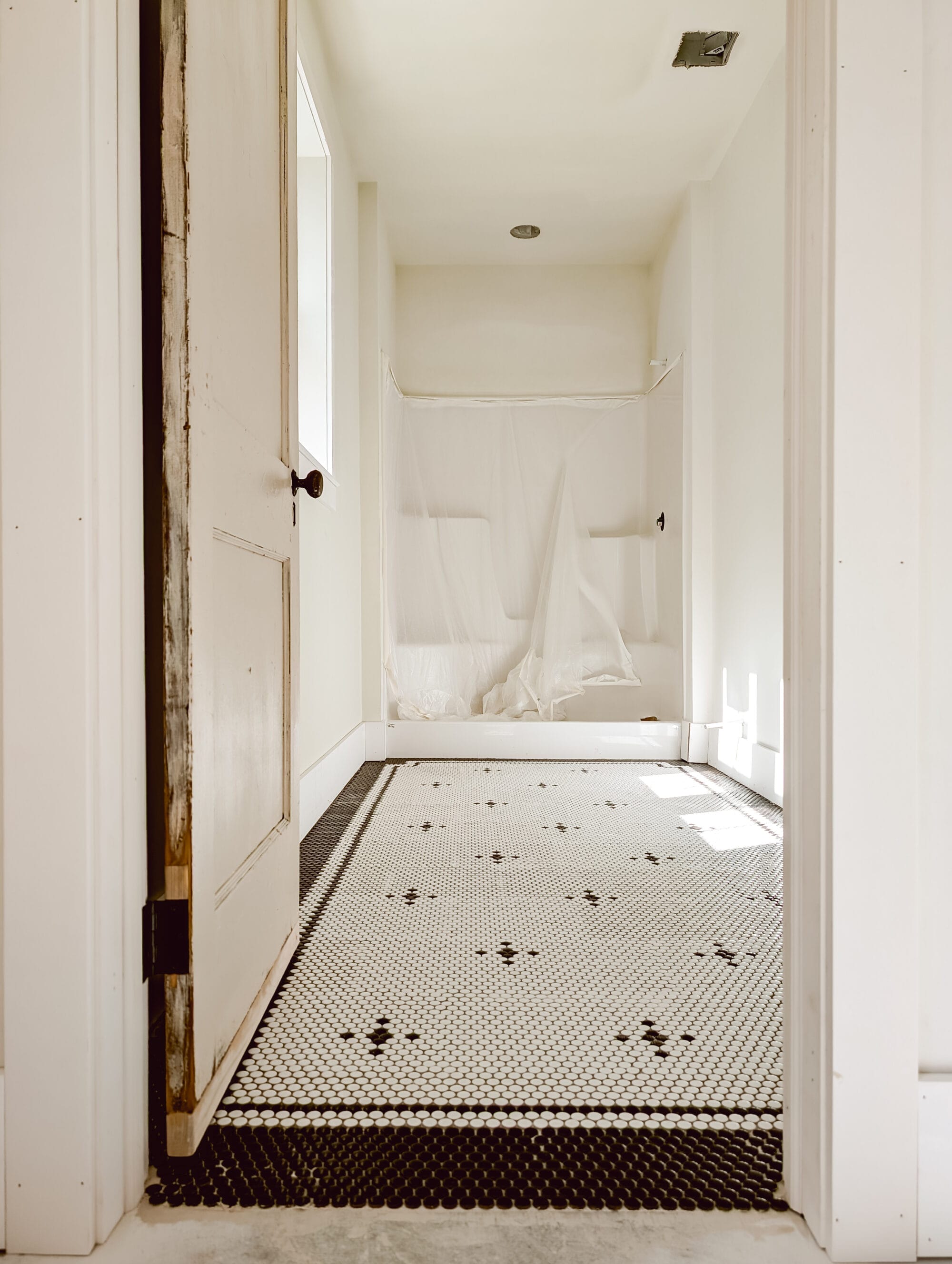 classic black and white penny tile floor pattern with a double border in our unfinished cottage bathroom