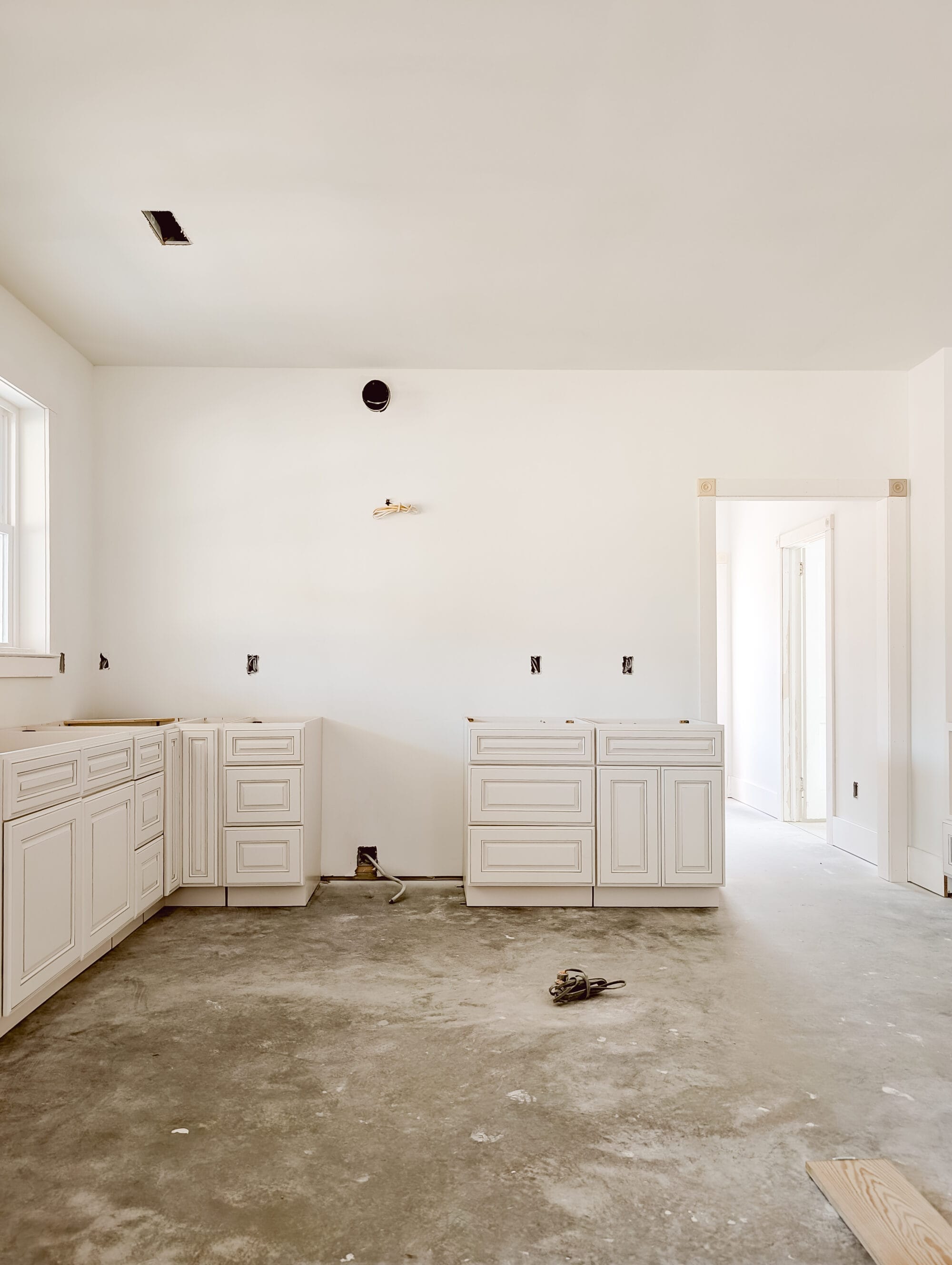unfinished new old cottage kitchen with new cabinets, concrete subfloor and primed walls