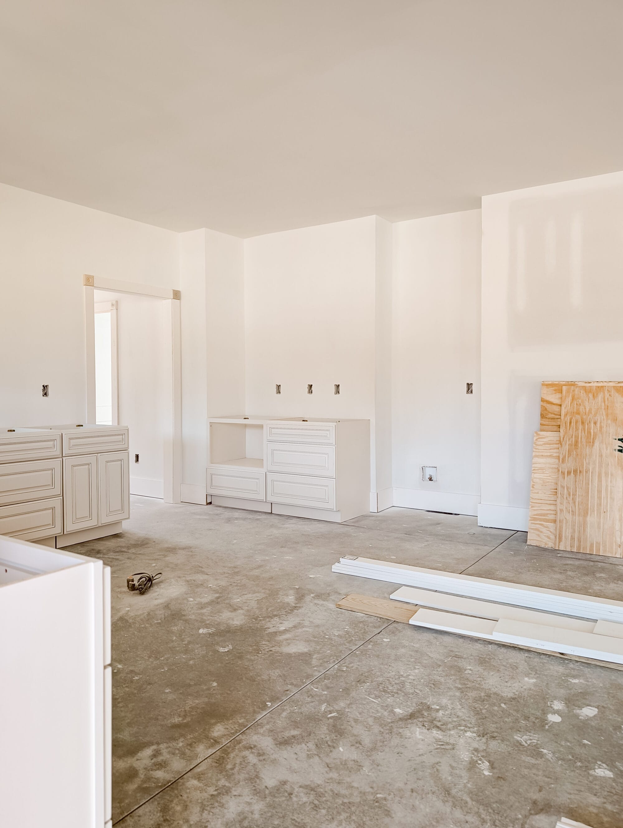 unfinished new old cottage kitchen with new cabinets, concrete subfloor and primed walls