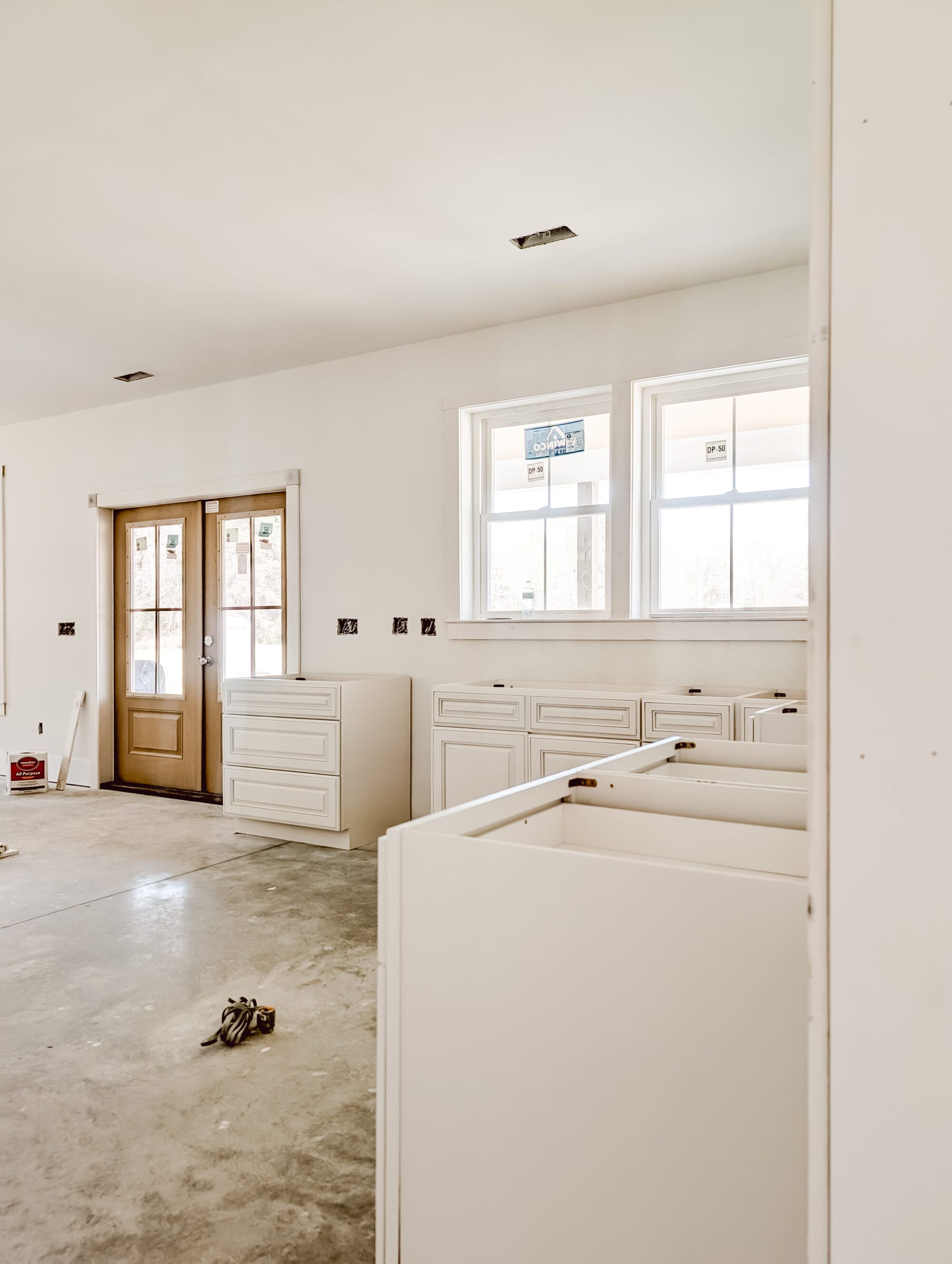 inside our unfinished new old cottage kitchen with new cabinets, concrete subfloor and primed walls