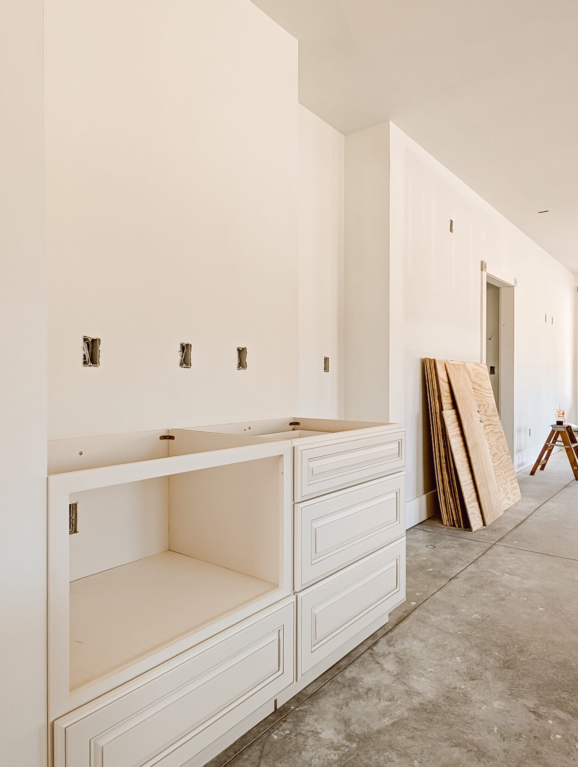 unfinished new old cottage kitchen with new cabinets, concrete subfloor and primed walls