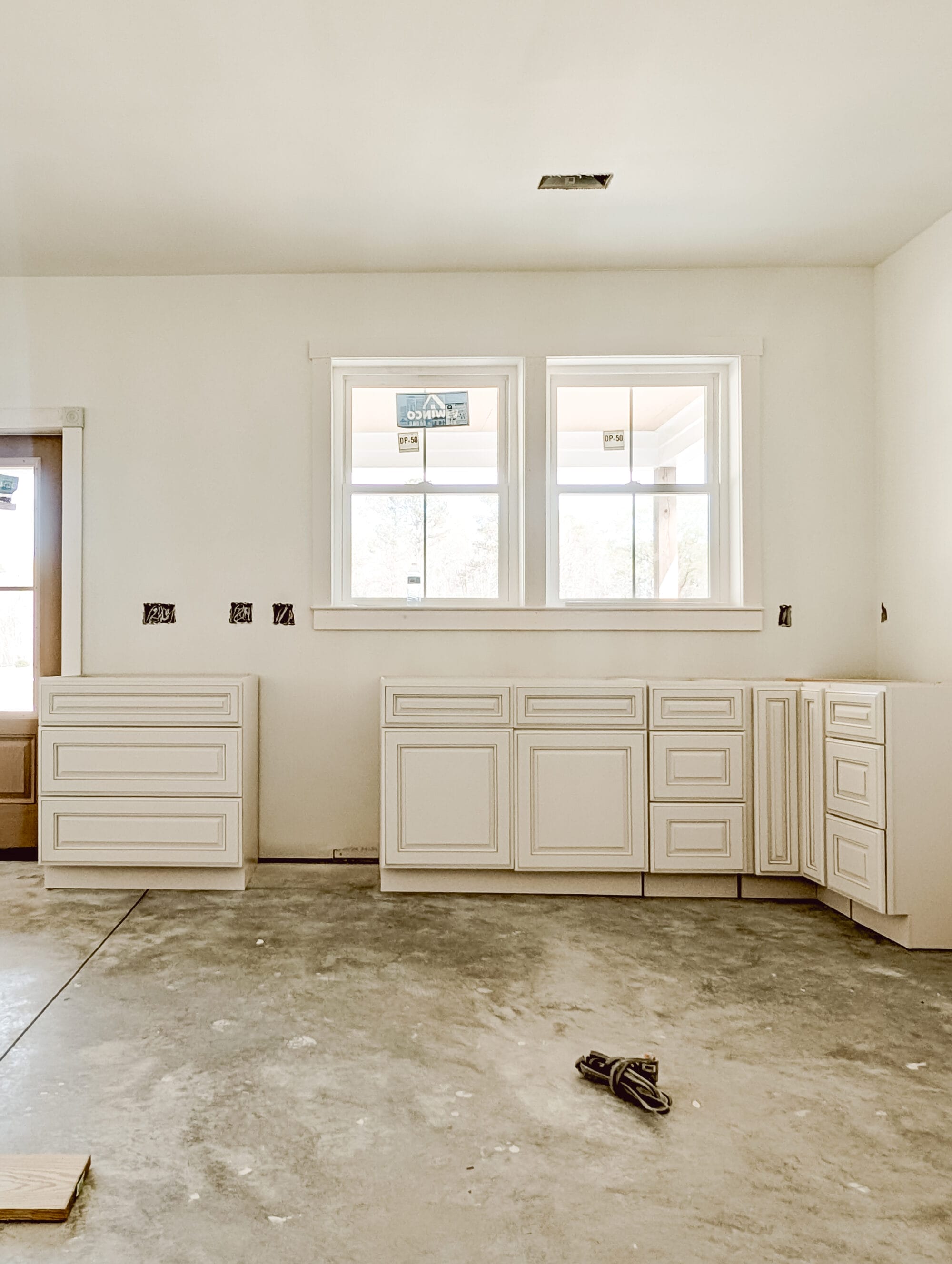 unfinished new old cottage kitchen with new cabinets, concrete subfloor and primed walls