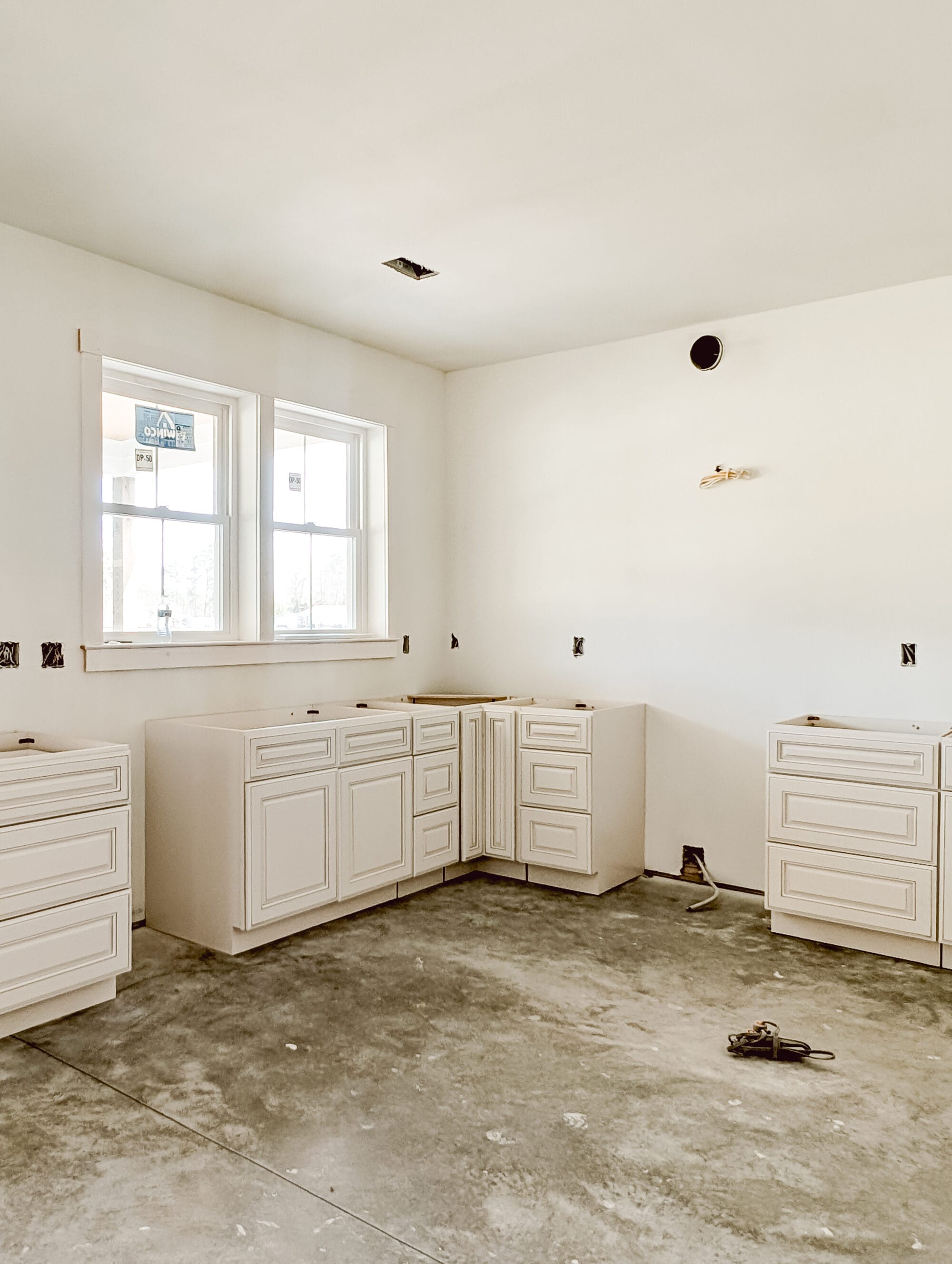 unfinished new old cottage kitchen with new cabinets, concrete subfloor and primed walls