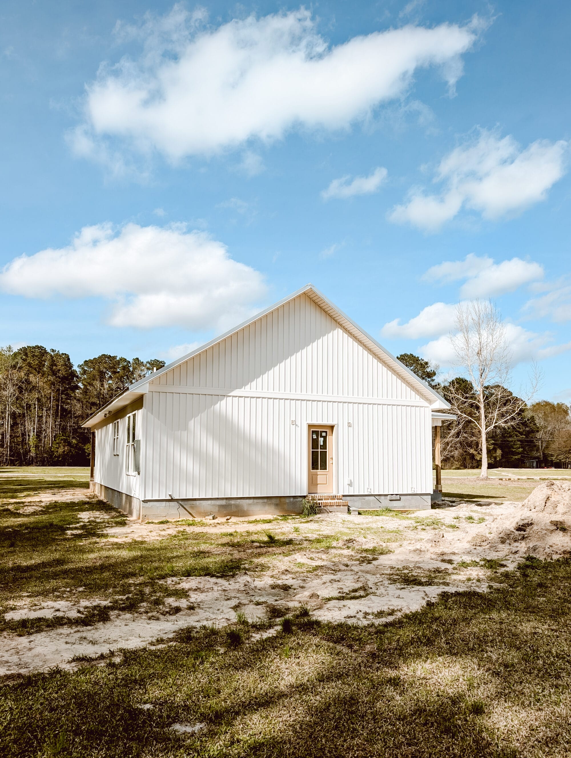 the back of our new old cottage still under construction with white board and batten siding and a 3/4 light glass back door