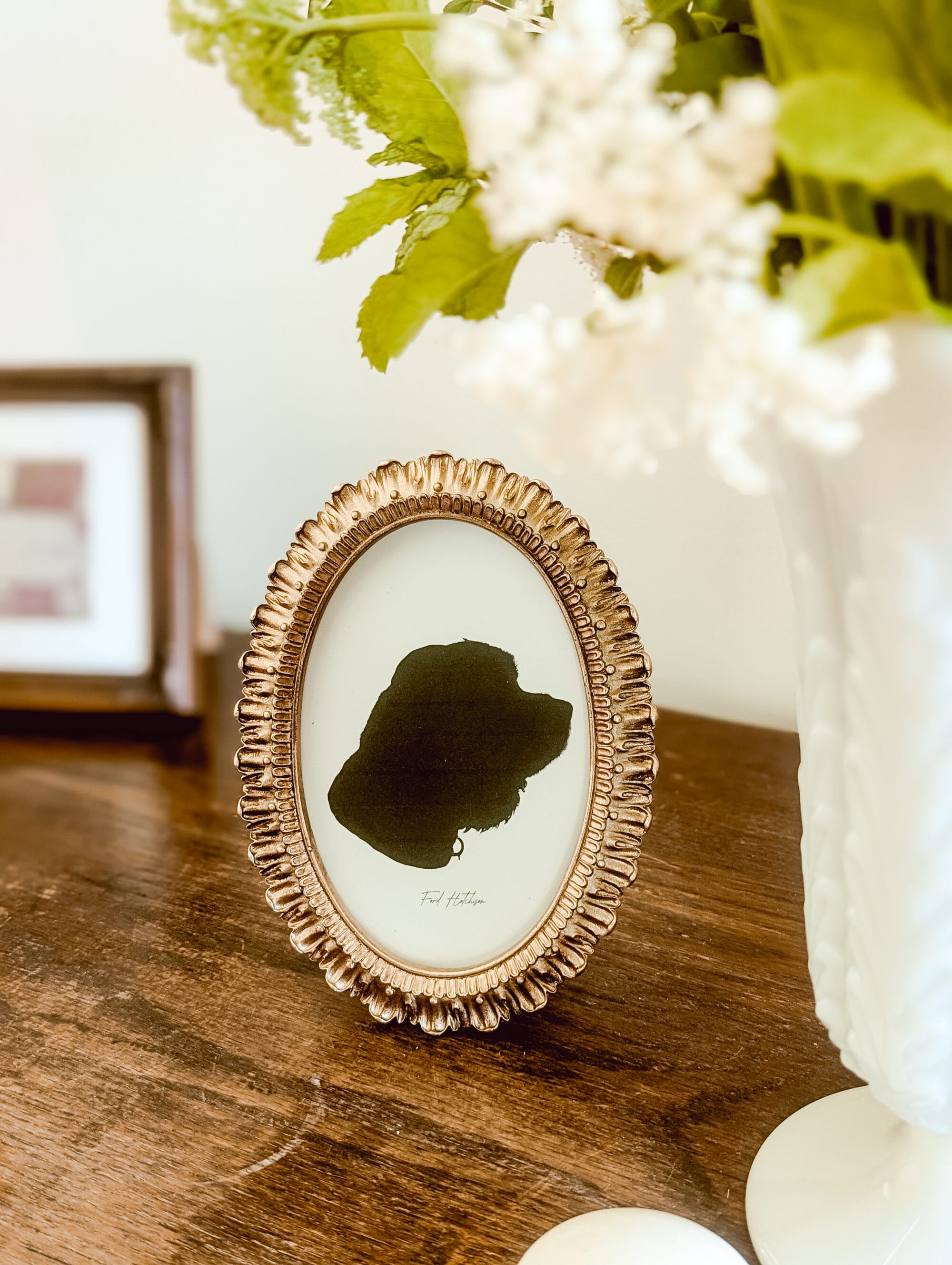 gold oval frame with black and white silhouette portrait of a cocker spaniel dog