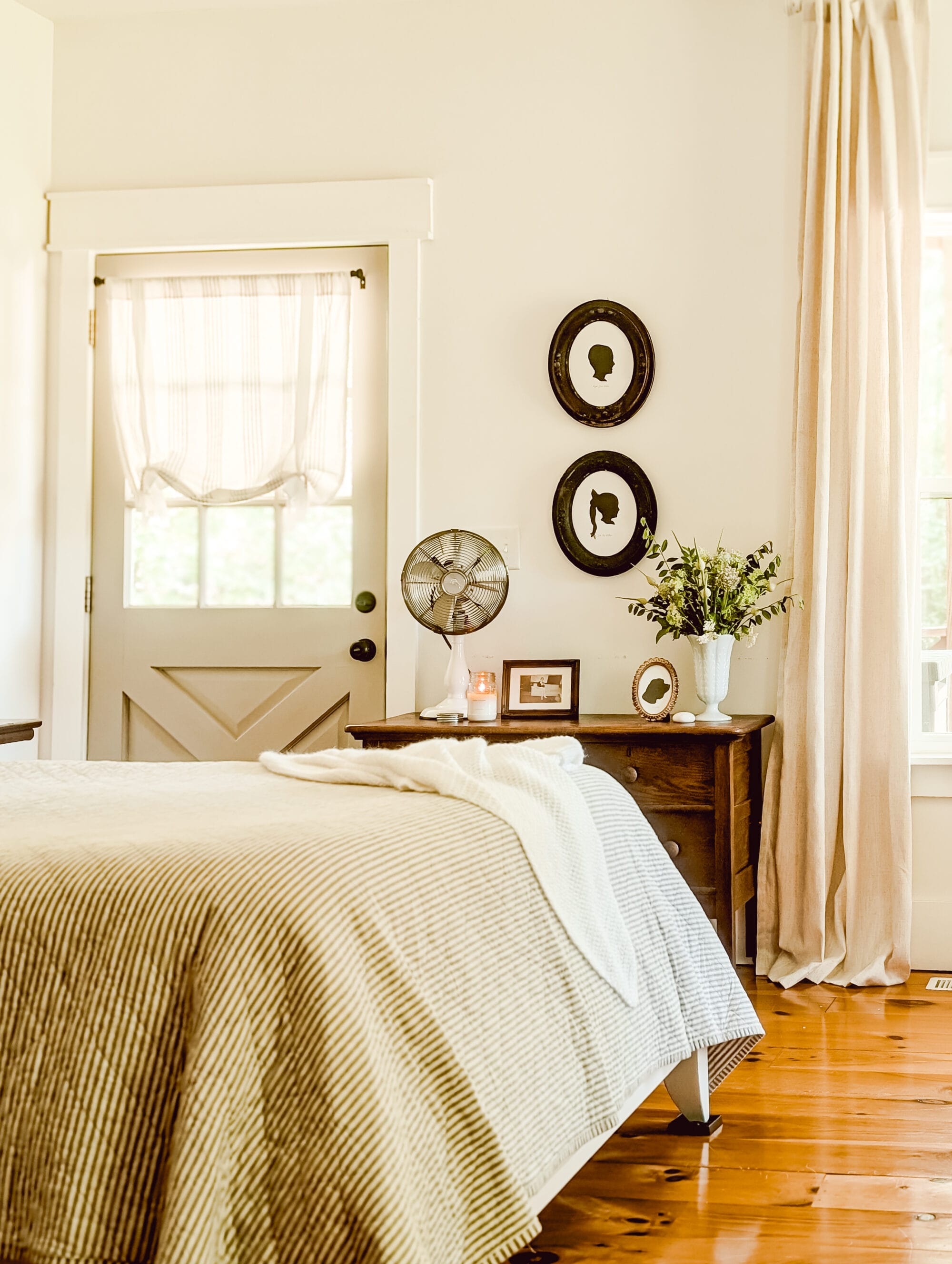 framed black and white silhouette portraits hung on the wall over an old wood dresser in a neutral farmhouse bedroom
