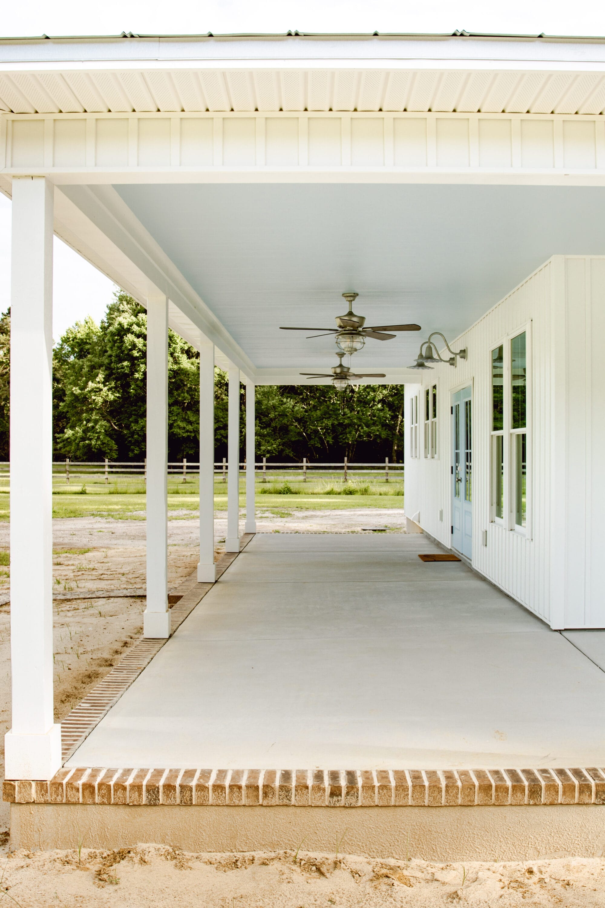haint blue porch ceilings on a white cottage house with galvanized exterior lighting and blue front door