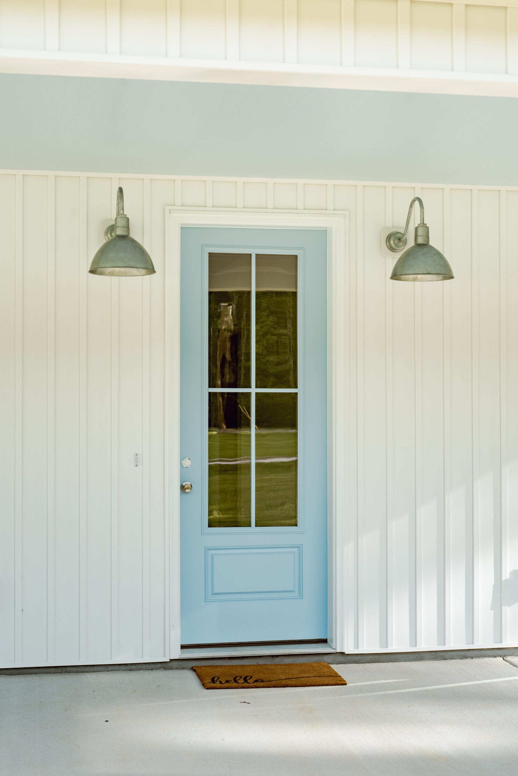 blue entry door on a white porch with galvanized exterior lights on either side of the door