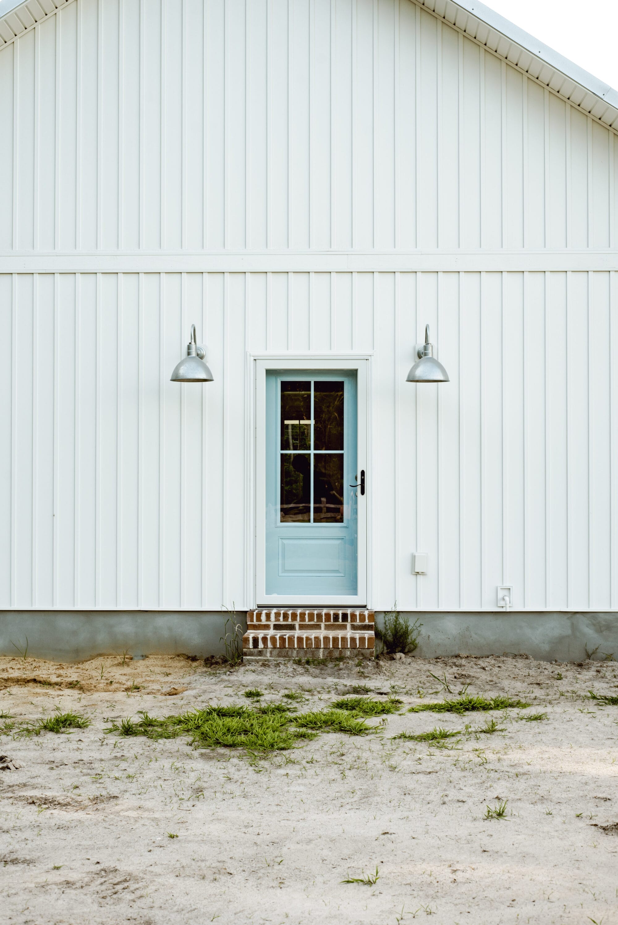 galvanized gooseneck lights from Barn Light Electric on a white cottage with blue door