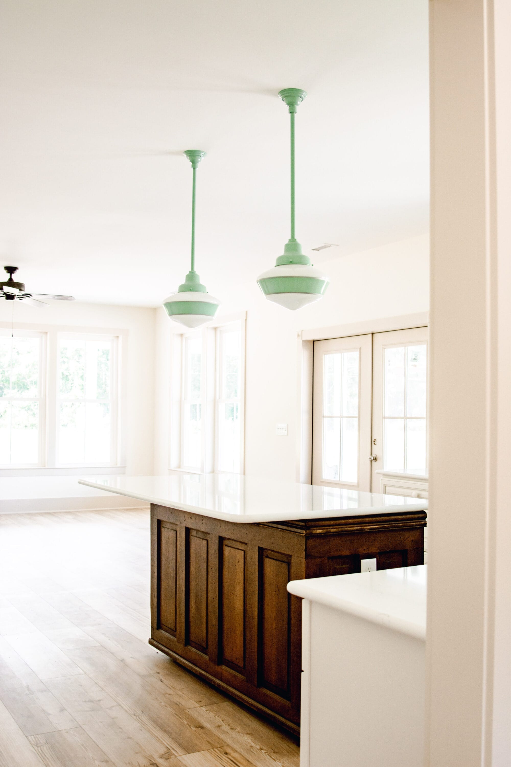 antique general store counter kitchen island with white quartz countertop and 2 vintage schoolhouse pendant lights