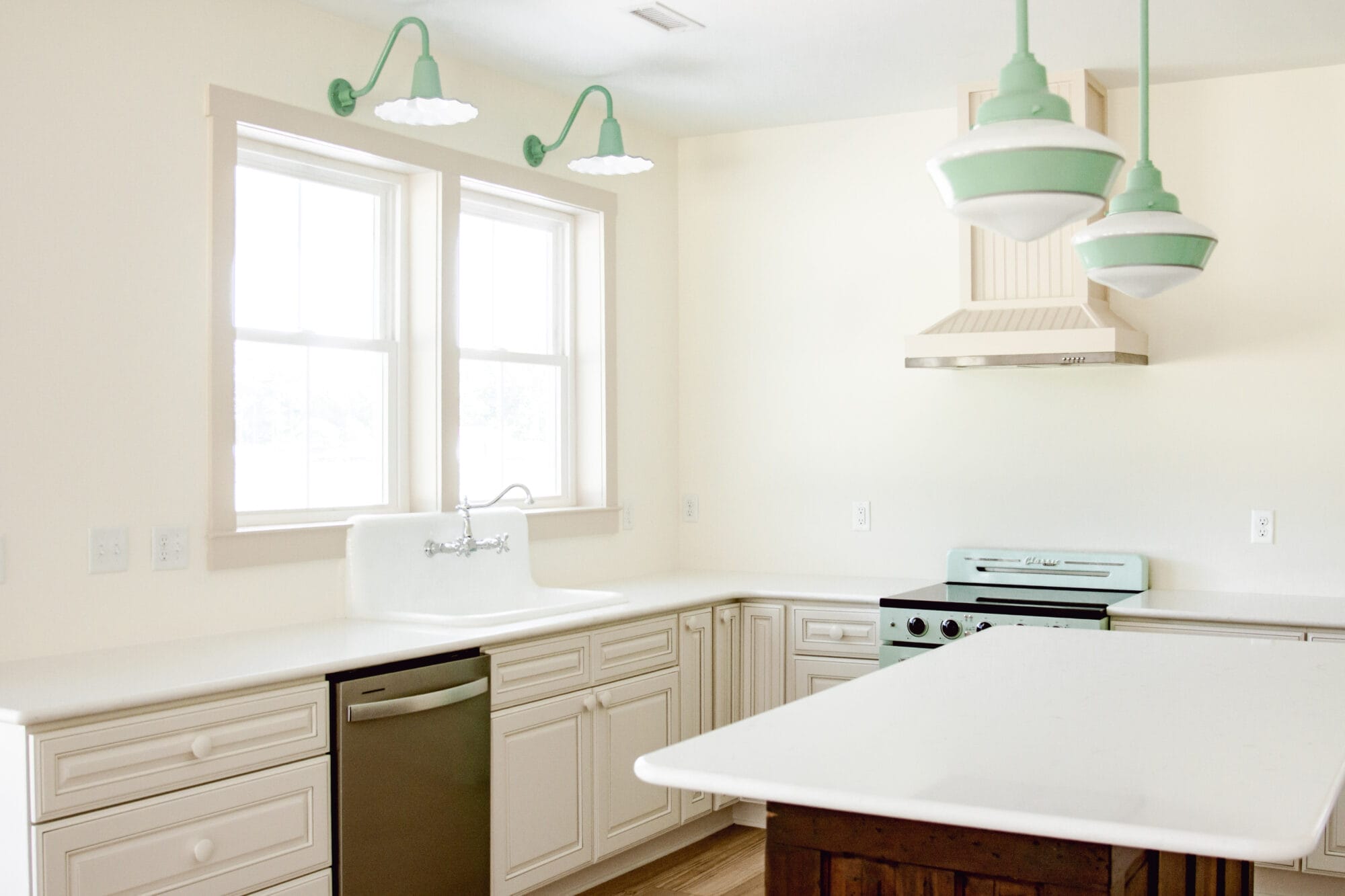 white cottage kitchen with white quartz countertops and pops of mint green in the lights and the appliances