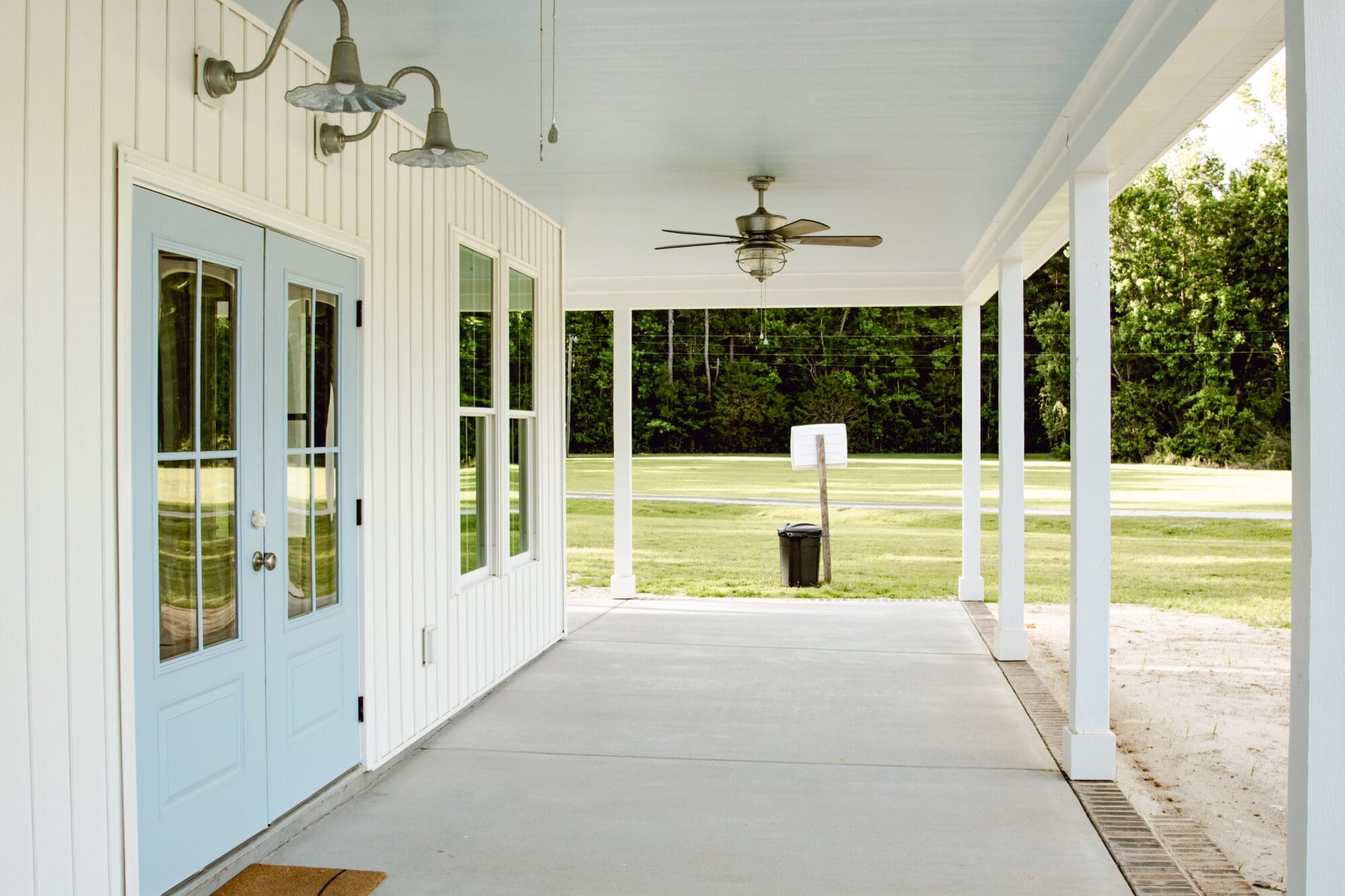 haint blue porch ceilings on a white cottage house with galvanized exterior lighting and blue double door