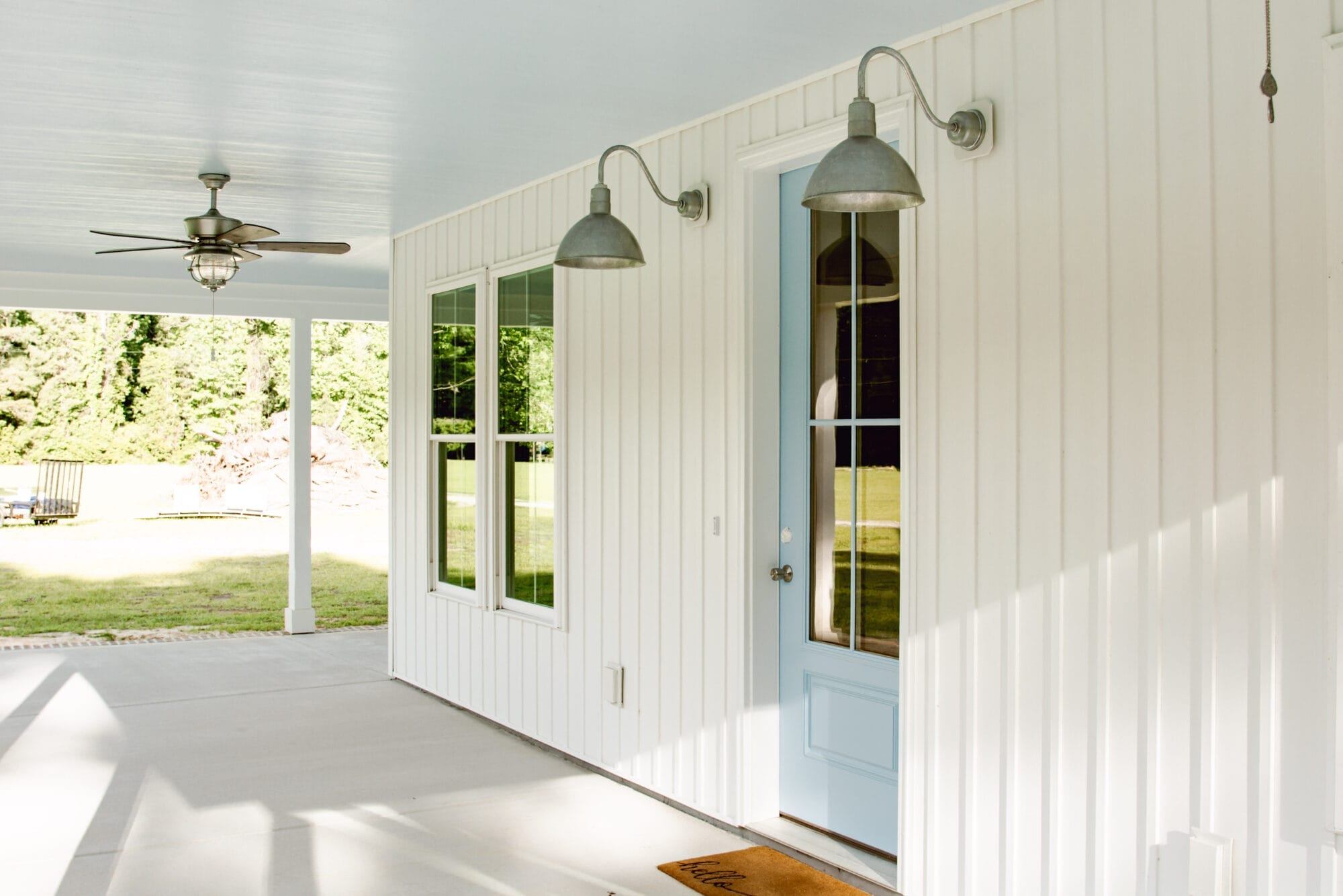 haint blue porch ceilings on a white cottage house with galvanized exterior lighting and blue front door