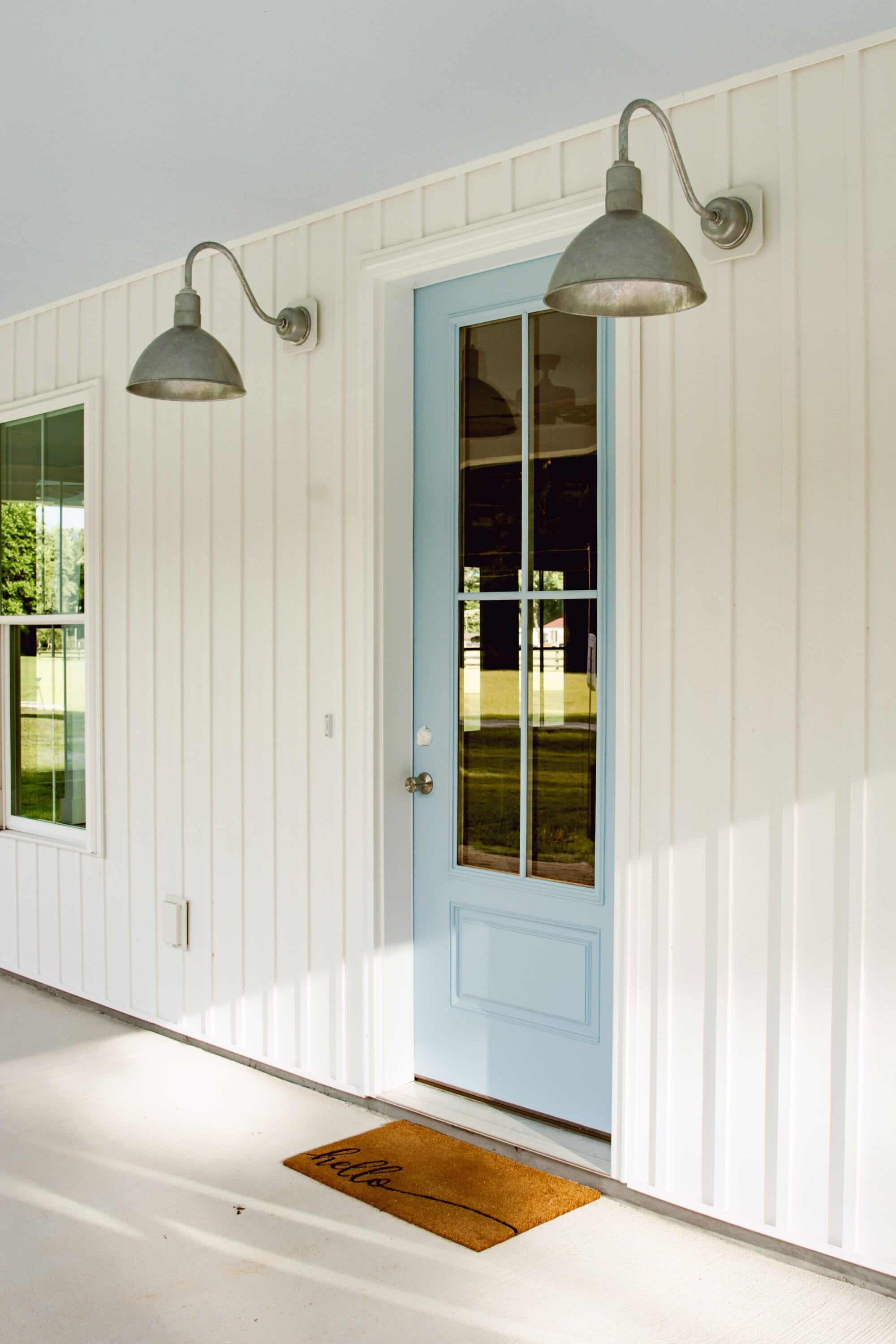 blue entry door on a white porch with galvanized exterior lights on either side of the door