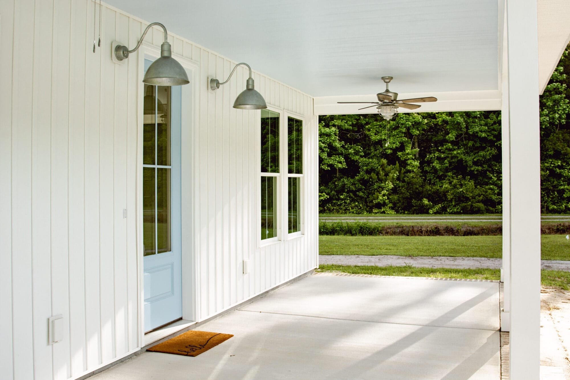 haint blue porch ceilings on a white cottage house with galvanized exterior lighting and blue front door