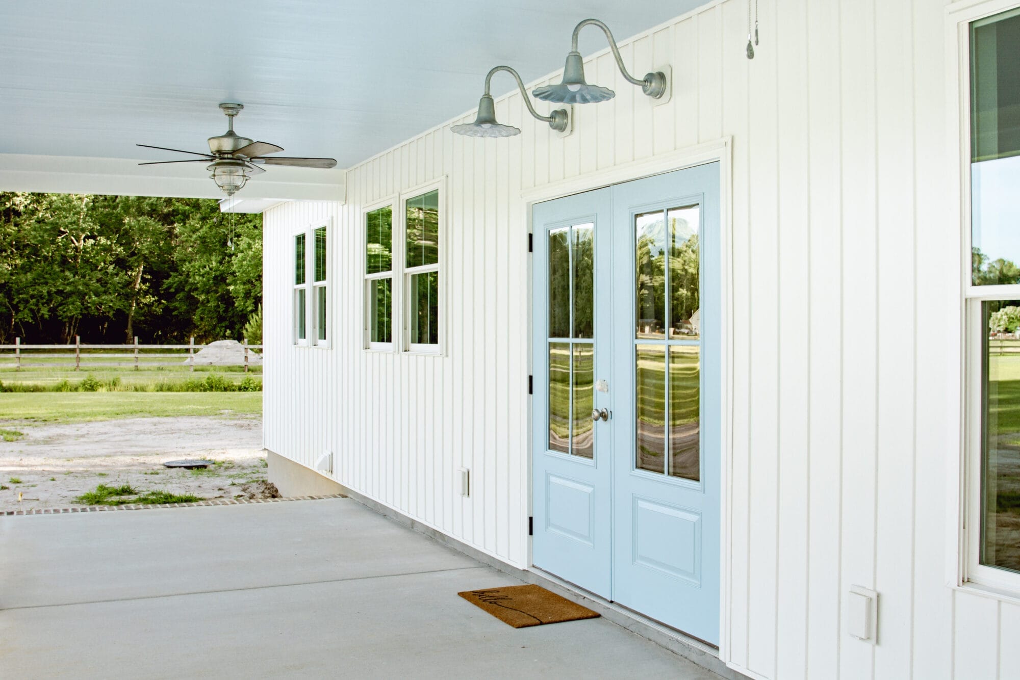 haint blue porch ceilings on a white cottage house with galvanized exterior lighting and blue double door
