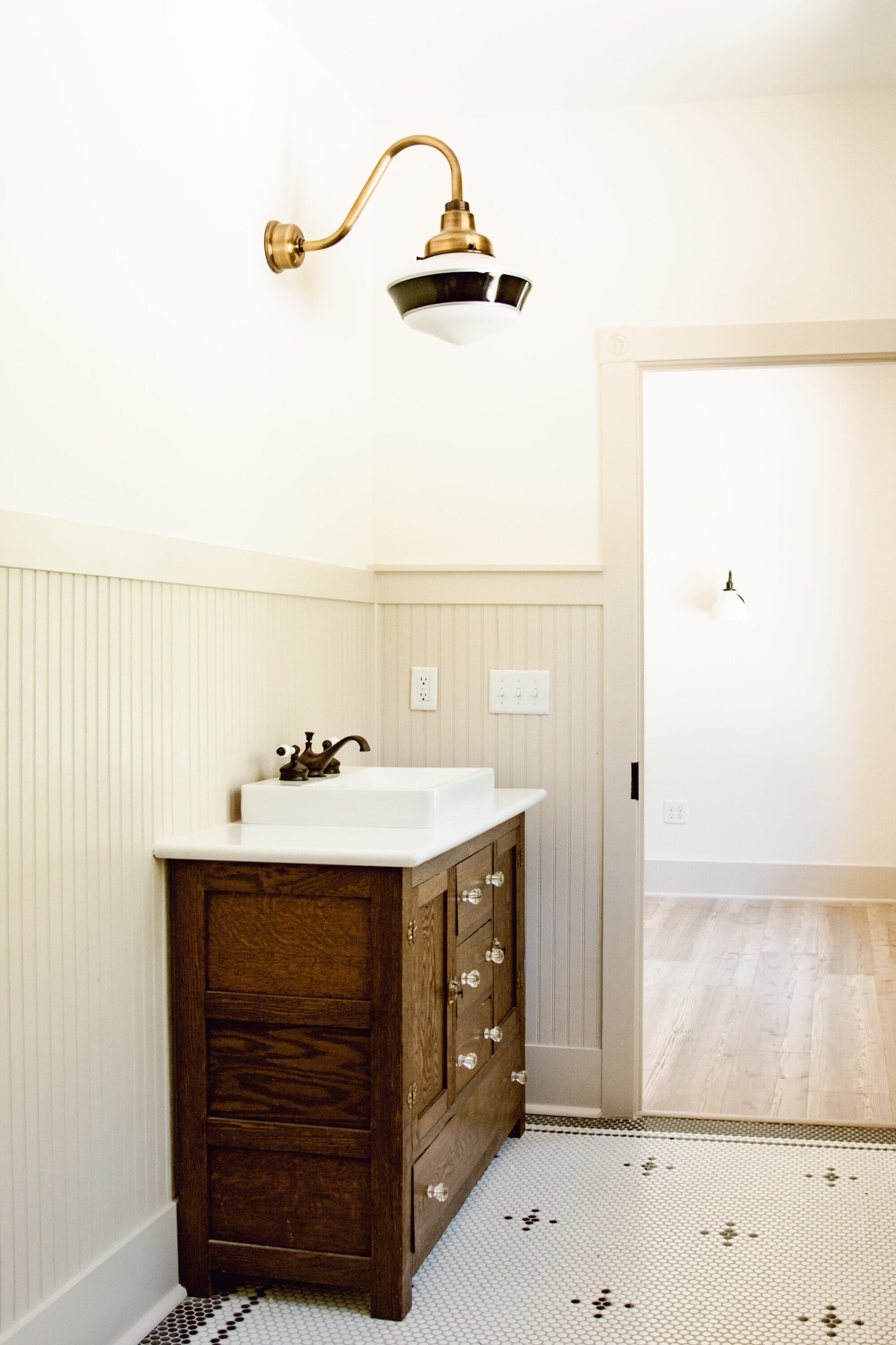 vintage cottage bathroom with antique buffet turned vanity and black and white penny tile floors