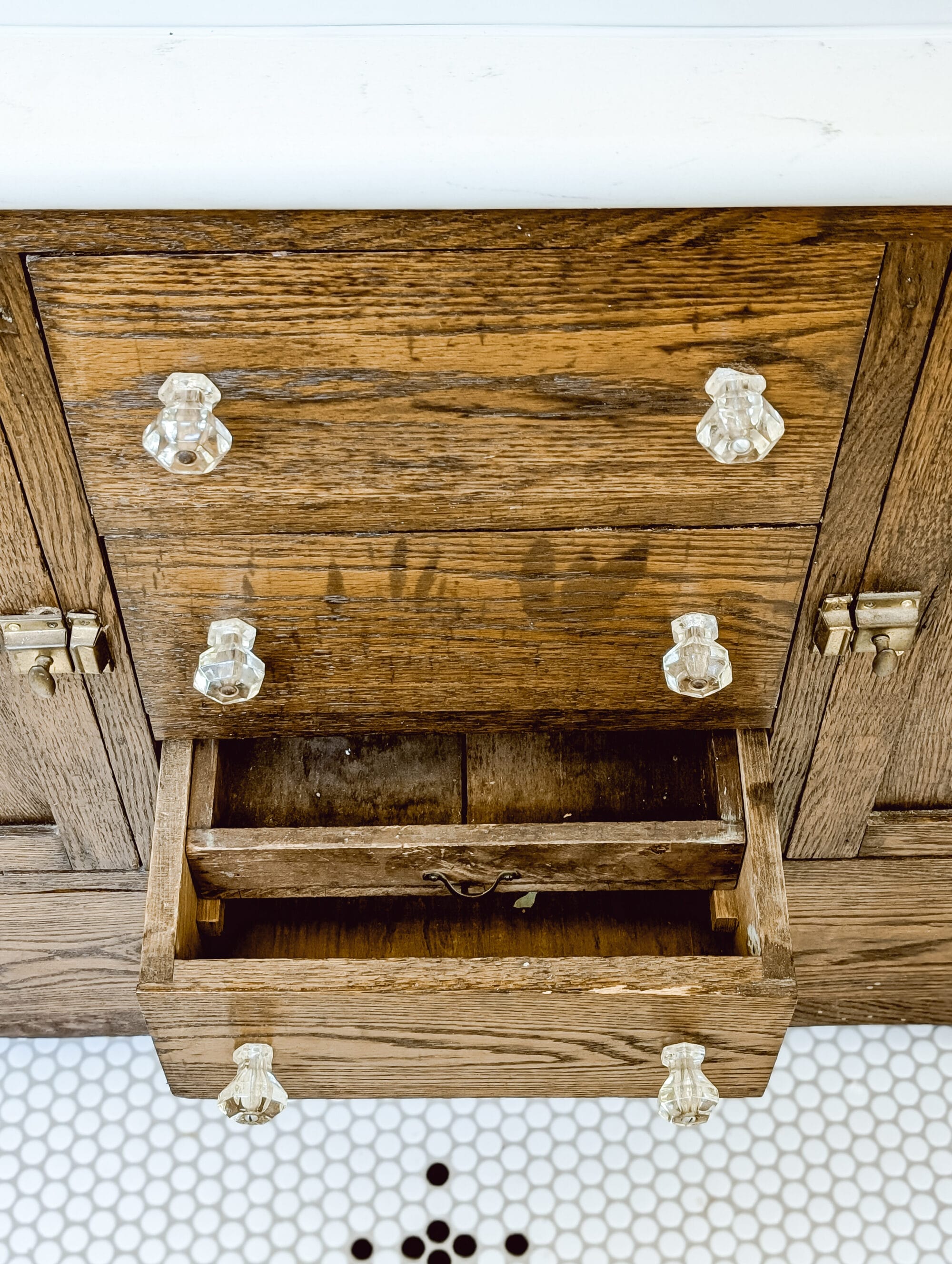 antique oak buffet with glass knobs turned into a bathroom vanity with white quartz countertop