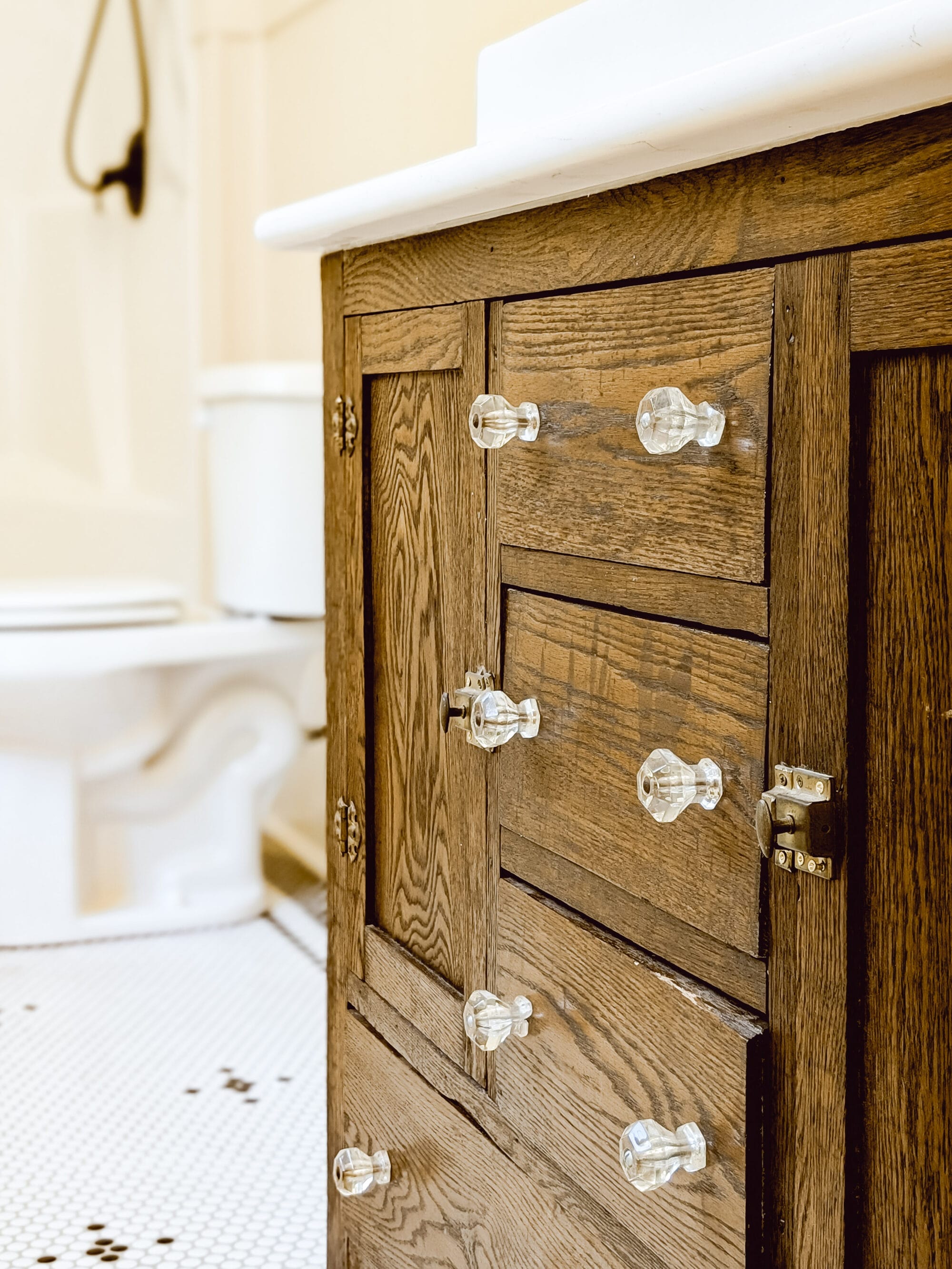 antique oak buffet with glass knobs turned into a bathroom vanity with white quartz countertop