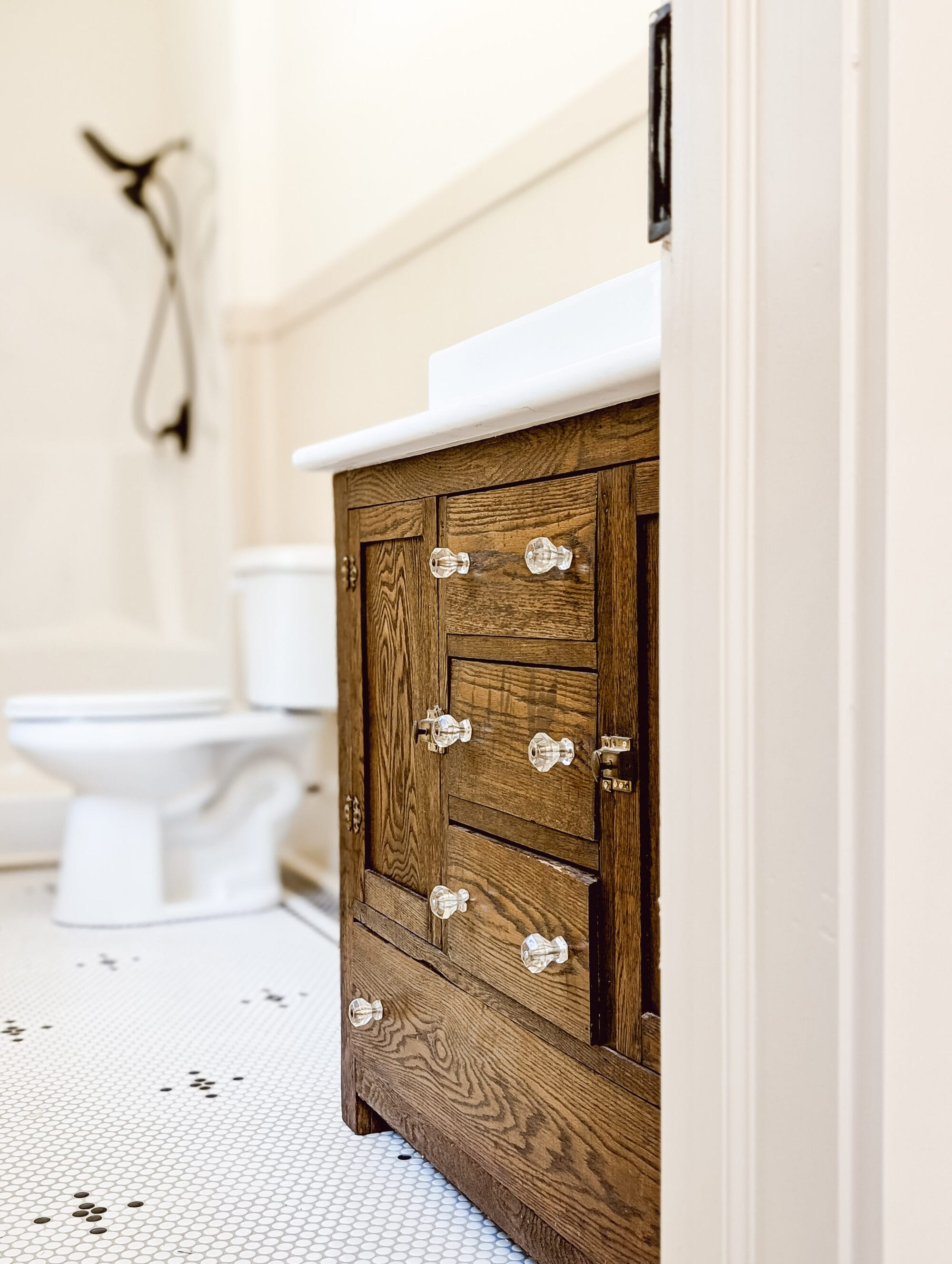 antique oak buffet with glass knobs turned into a bathroom vanity with white quartz countertop