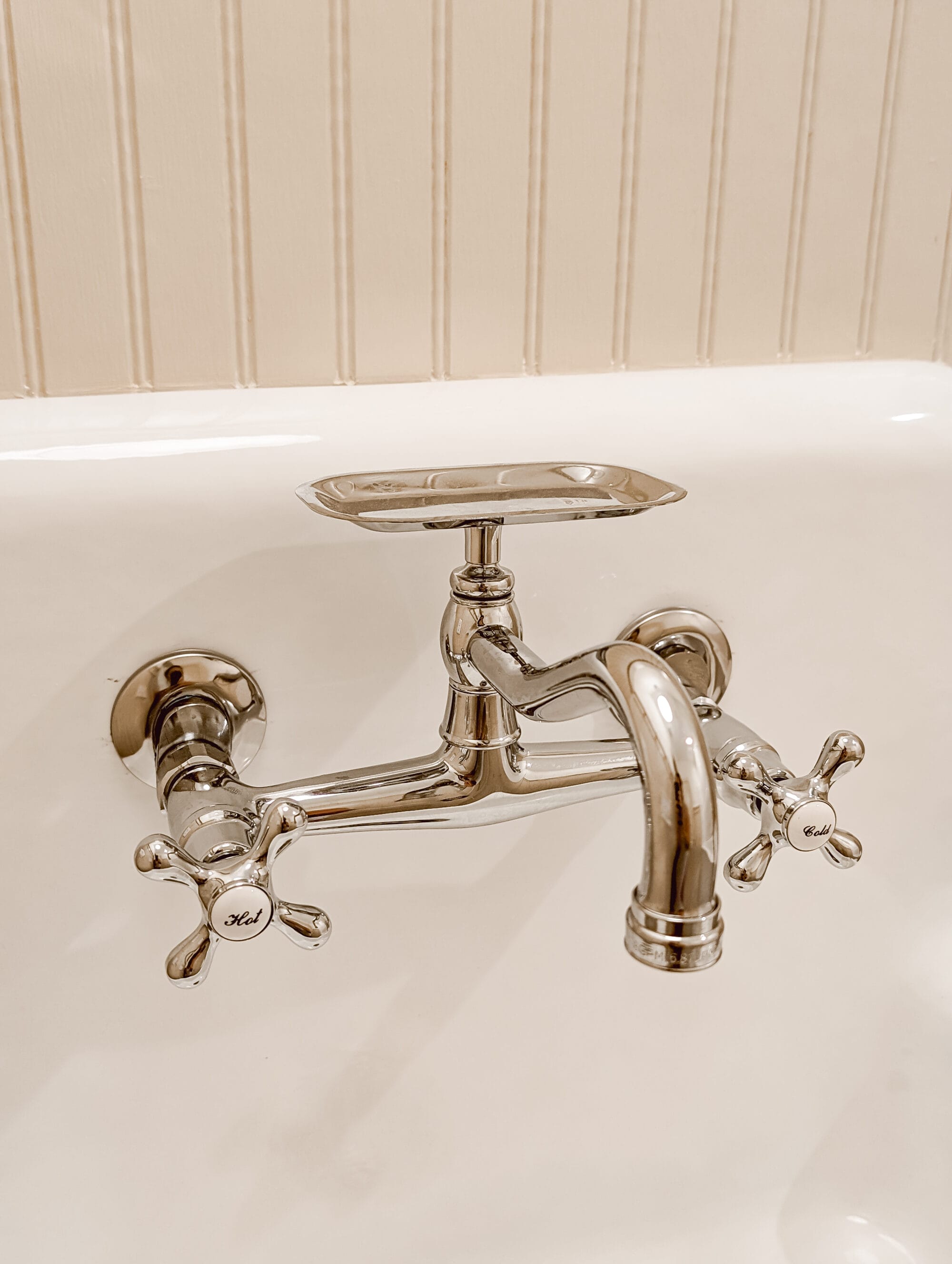 vintage inspired chrome faucet with "hot" and "cold" knobs and a built-in soap dish