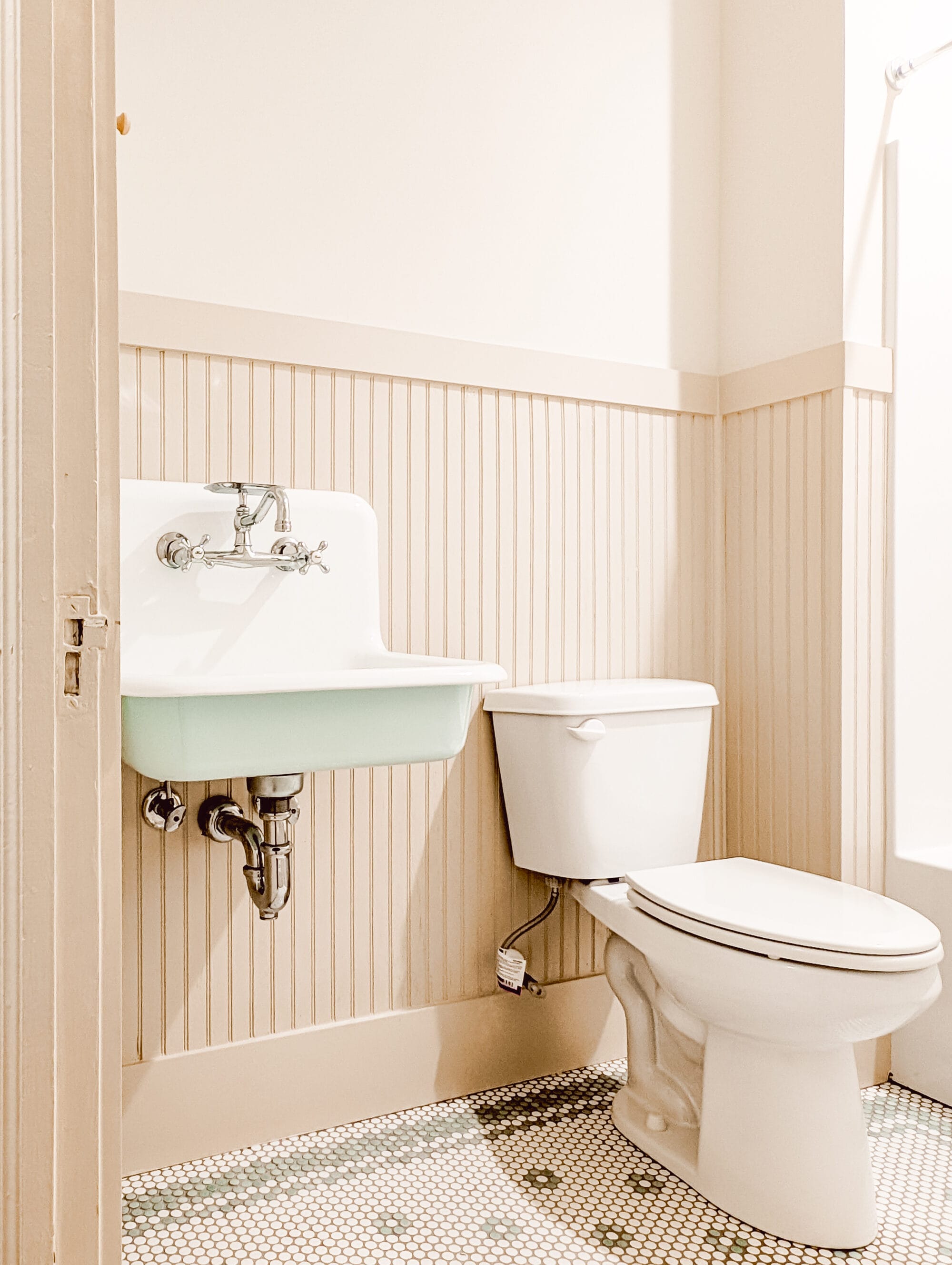 old fashioned wall mount sink with mint green painted bottom and mint green and white penny tile floors