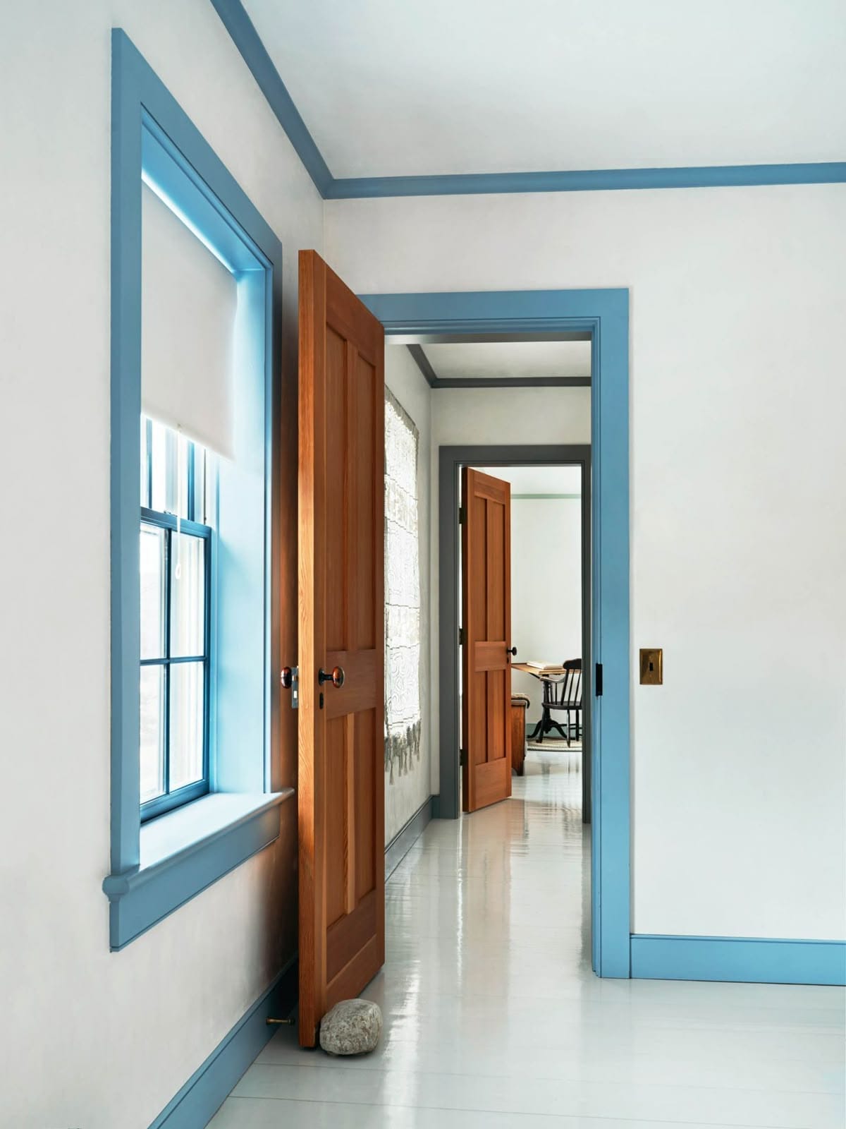blue trim around the windows, doors, and blue baseboards inside a home with white walls and white painted floors