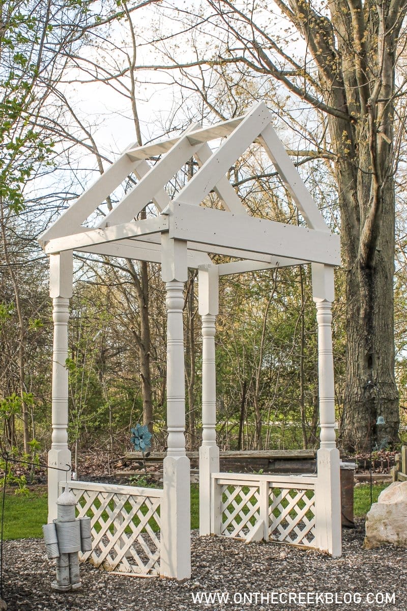 white painted garden arbor made from two salvaged porch posts, lattice, and treated lumber