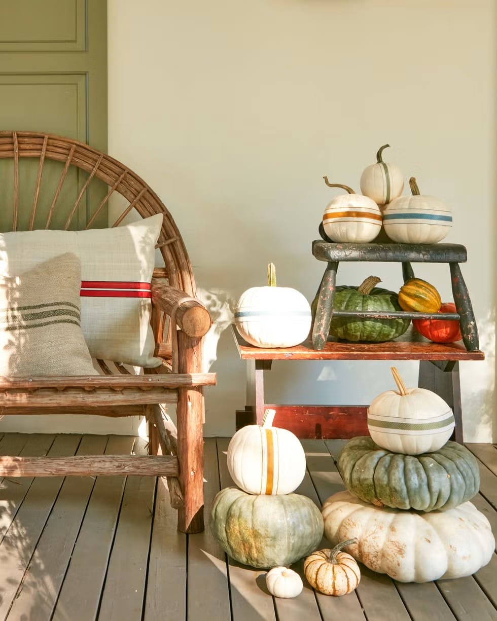 grainsack striped pumpkins stacked on the front porch