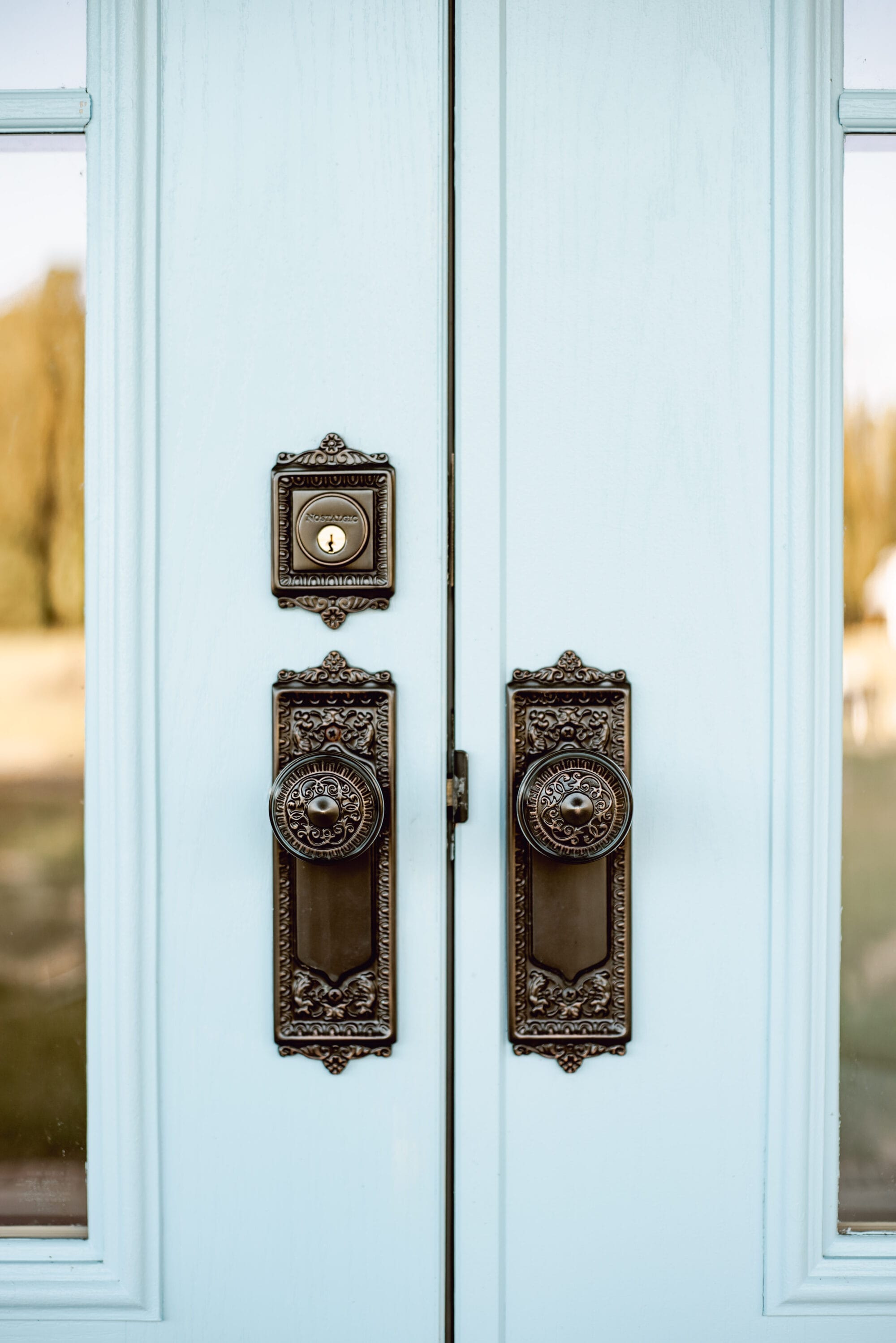 blue exterior doors with vintage-inspired Egg & Dart style door knobs in Timeless Bronze from Nostalgic Warehouse 