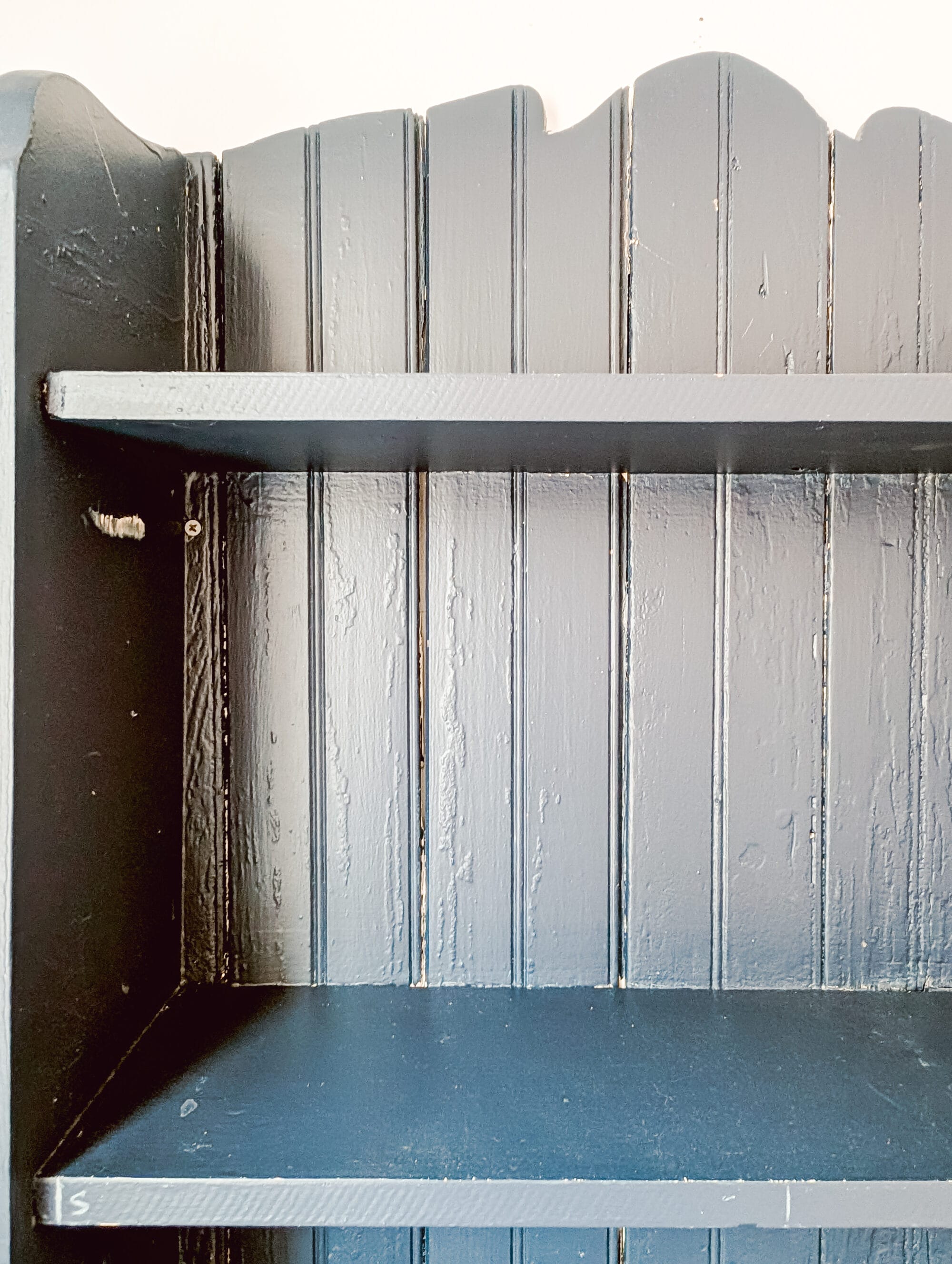tongue and groove boards covered in layers of old paint on the back of a thrifted bookcase